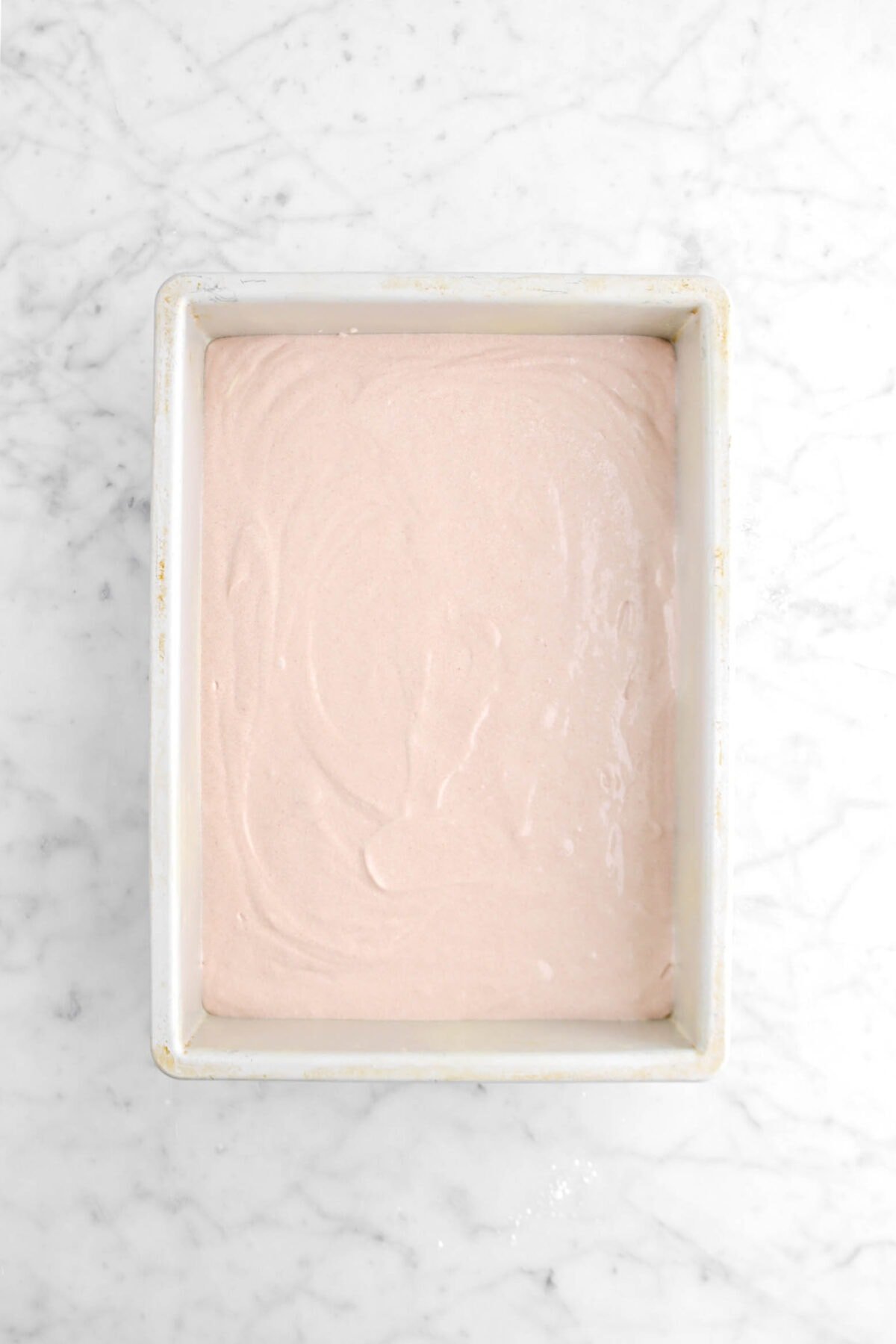 strawberry cake batter in sheet pan on marble surface