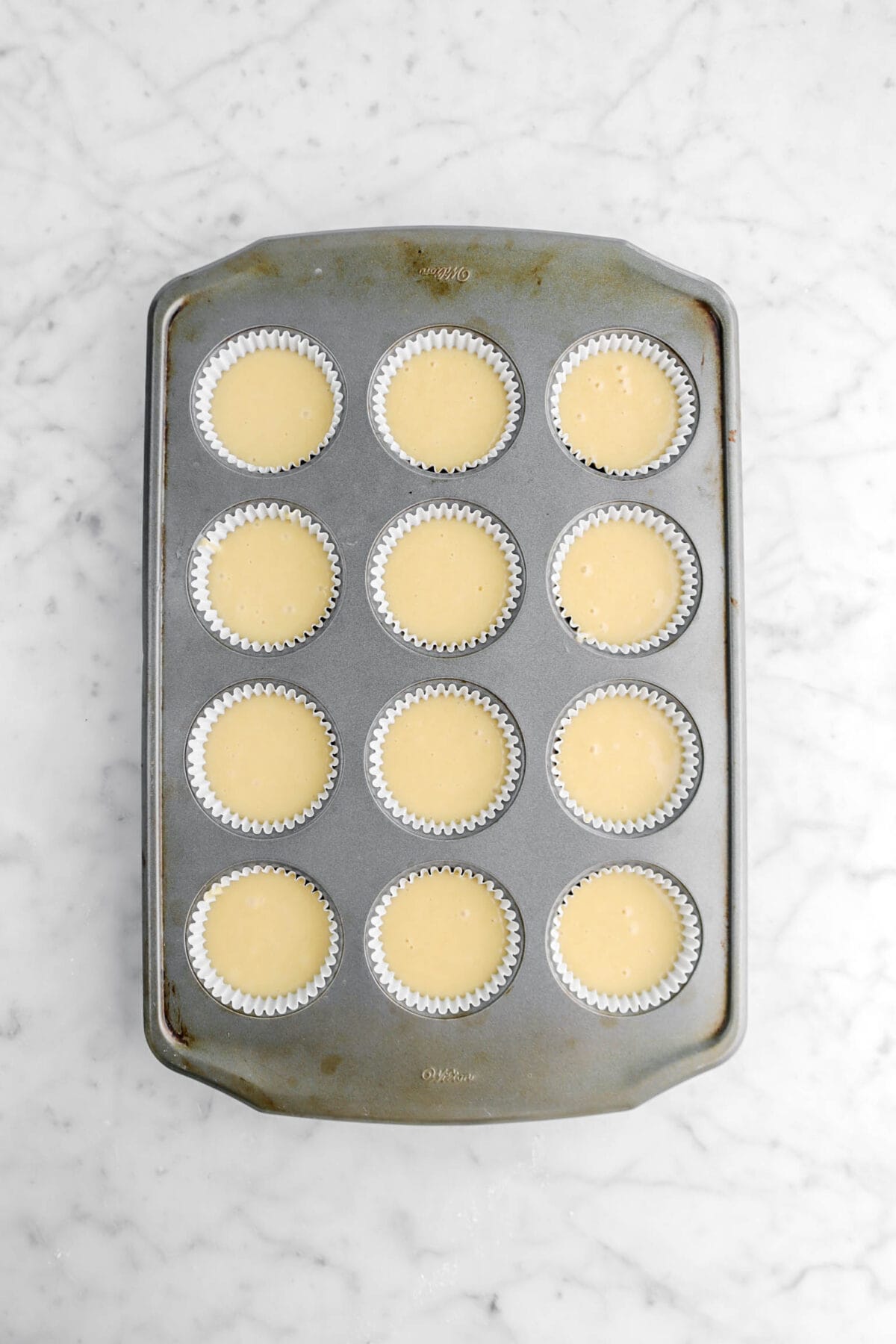 cupcake batter in lined cupcake pan on marble surface