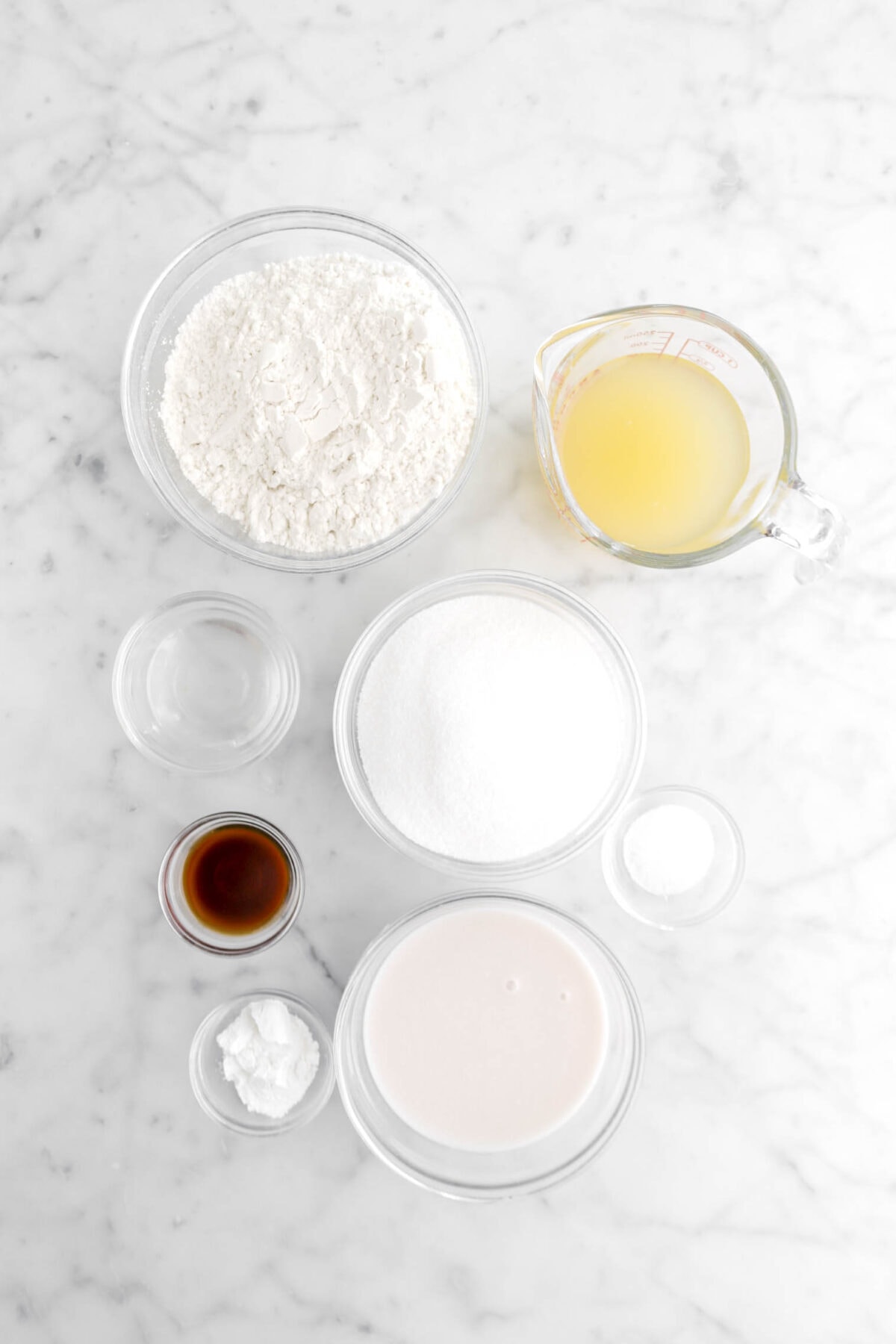 flour, aquafaba, coconut oil, sugar, salt, vanilla, coconut milk, and baking powder on marble surface