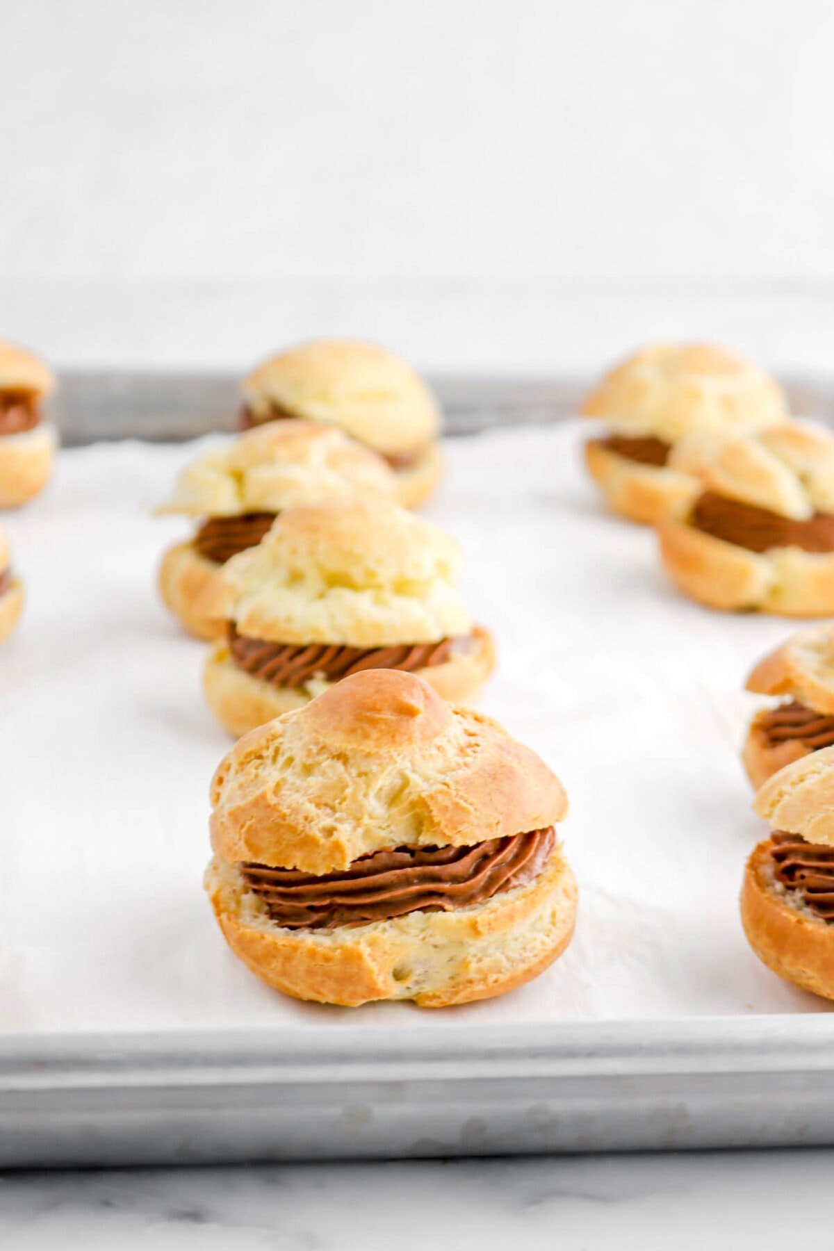 chocolate cream puffs on lined sheet pan