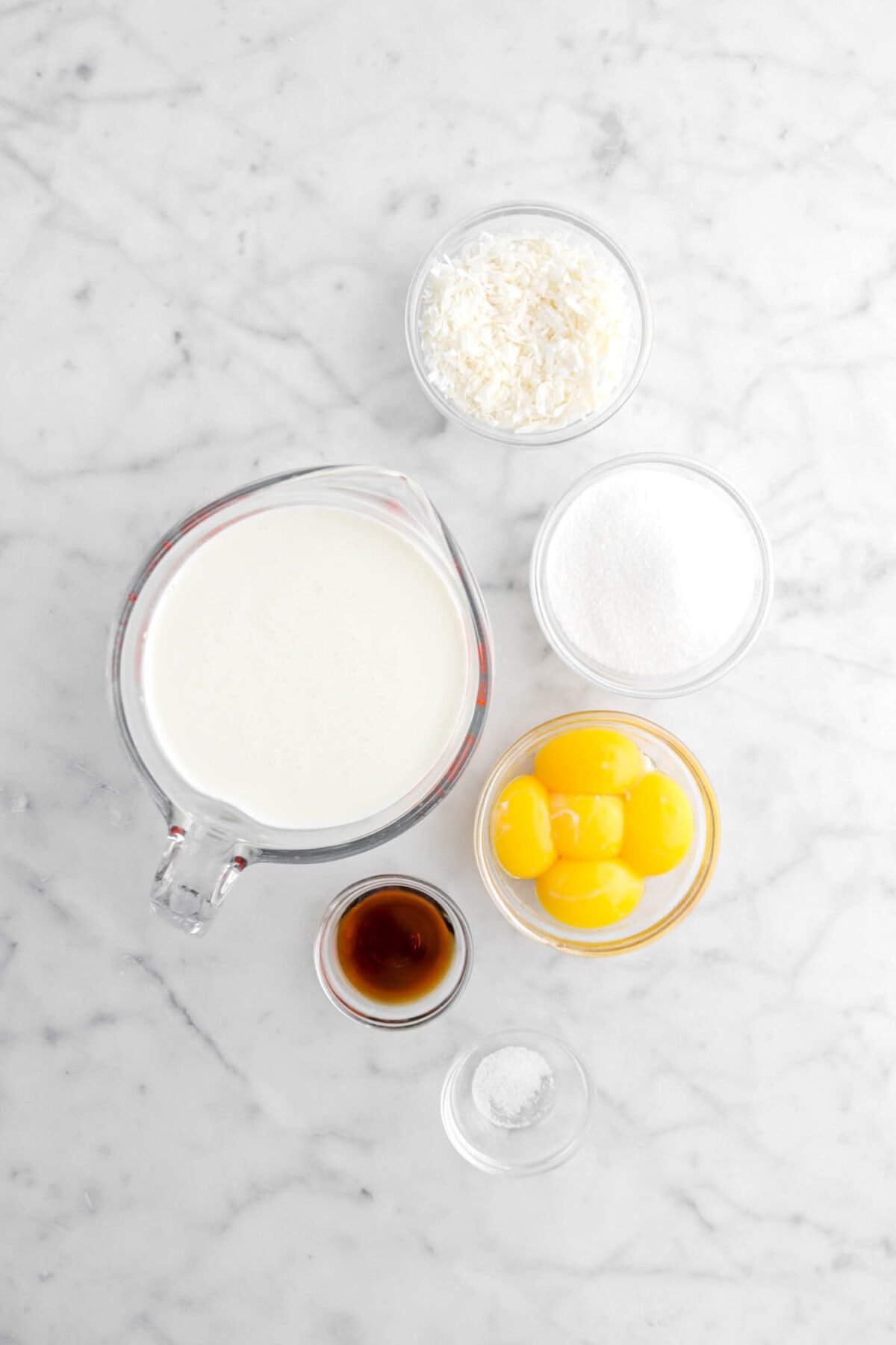 shredded coconut, sugar, egg yolks, heavy cream, vanilla, and salt on marble surface