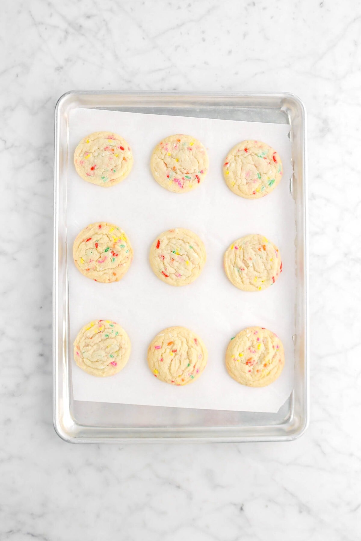 twelve baked funfetti cookies on lined sheet pan