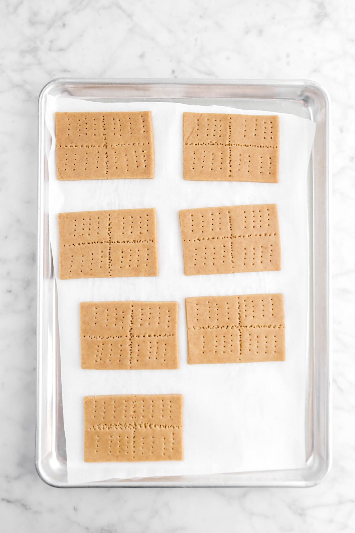 seven unbaked graham crackers on lined sheet pan