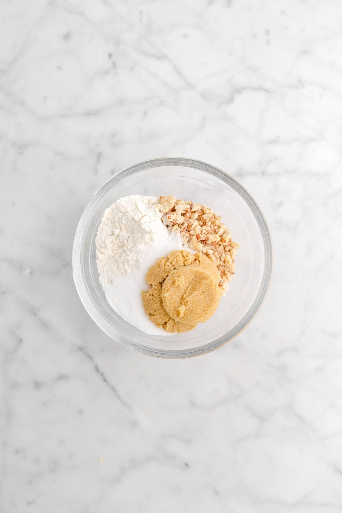 flour, sugar, brown sugar, and chopped almonds in glass bowl