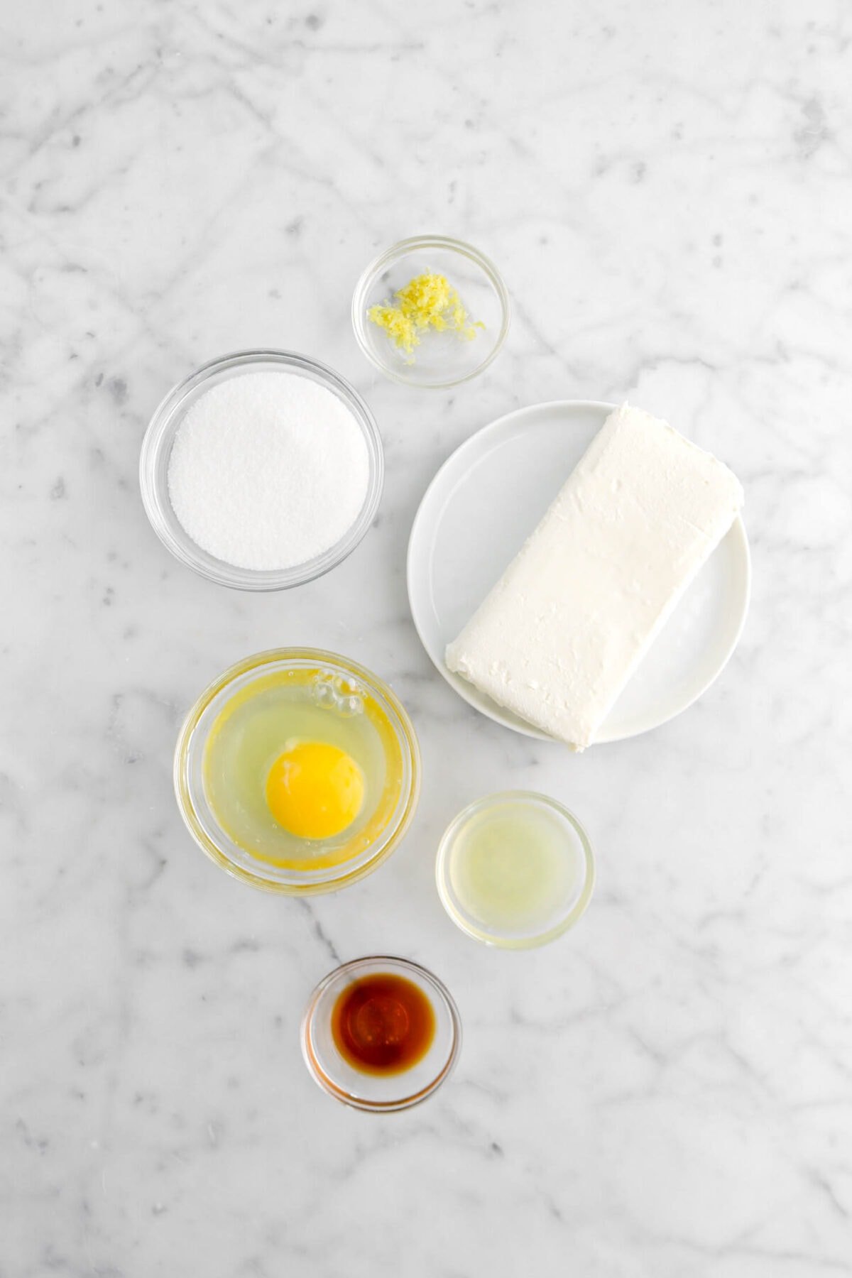 lemon zest, sugar, cream cheese, egg, lemon juice, and vanilla on marble surface