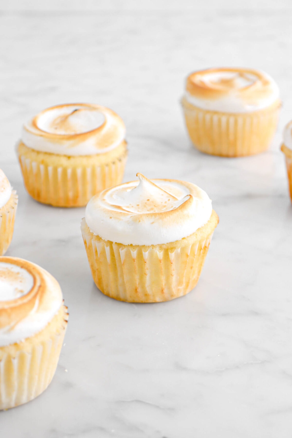 toasted meringue on top of cupcakes on marble surface