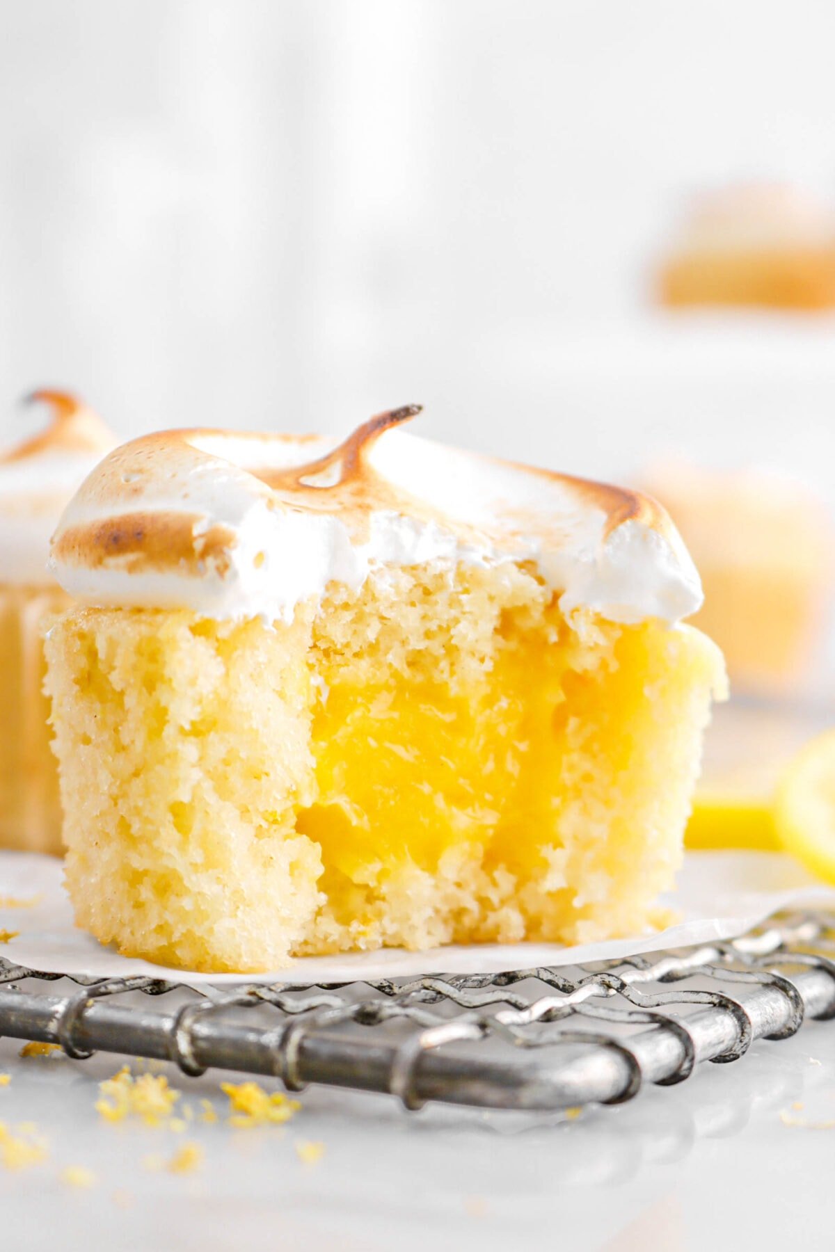 close up of lemon meringue cupcake with bite missing on wire cooling rack