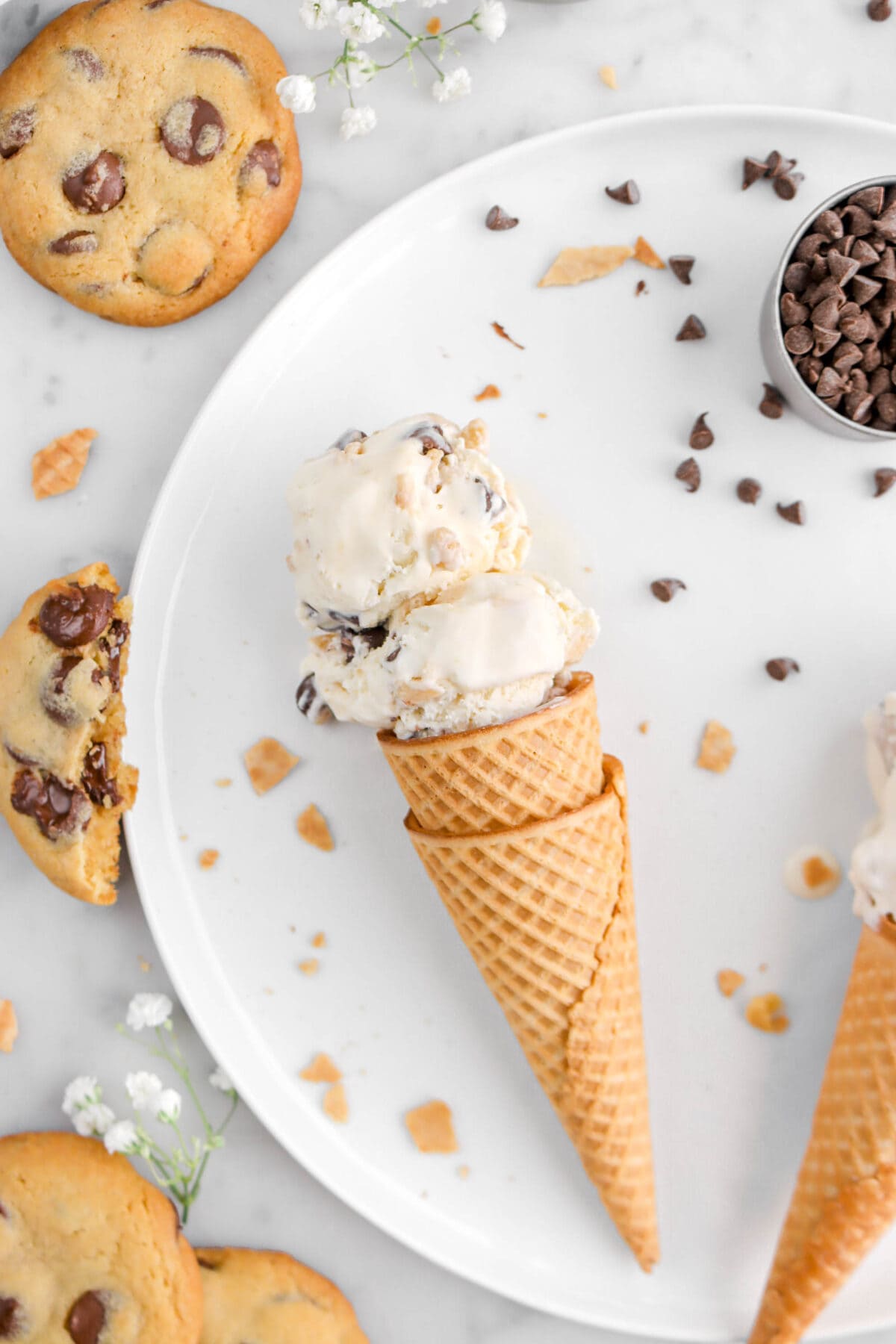close up of chocolate chip cookie dough ice cream on white plate with cookies beside