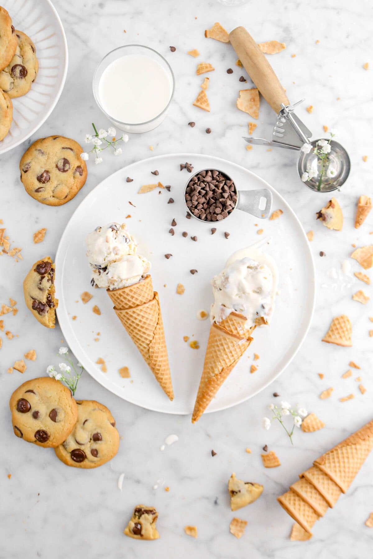 cookie dough ice cream on white plate with chocolate chip cookies beside and ice cream cone crumbs around