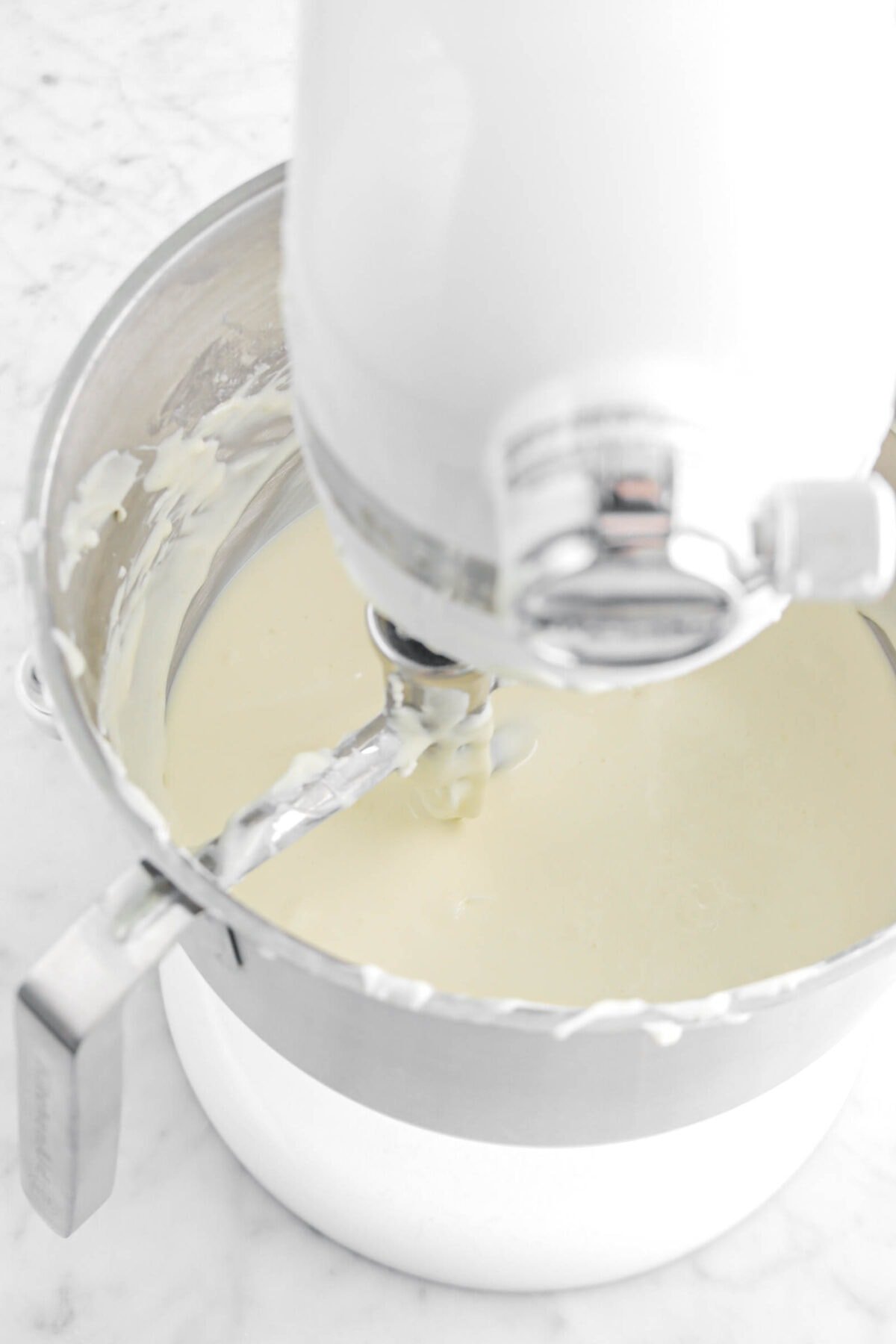 cheesecake filling in stand mixer on marble surface