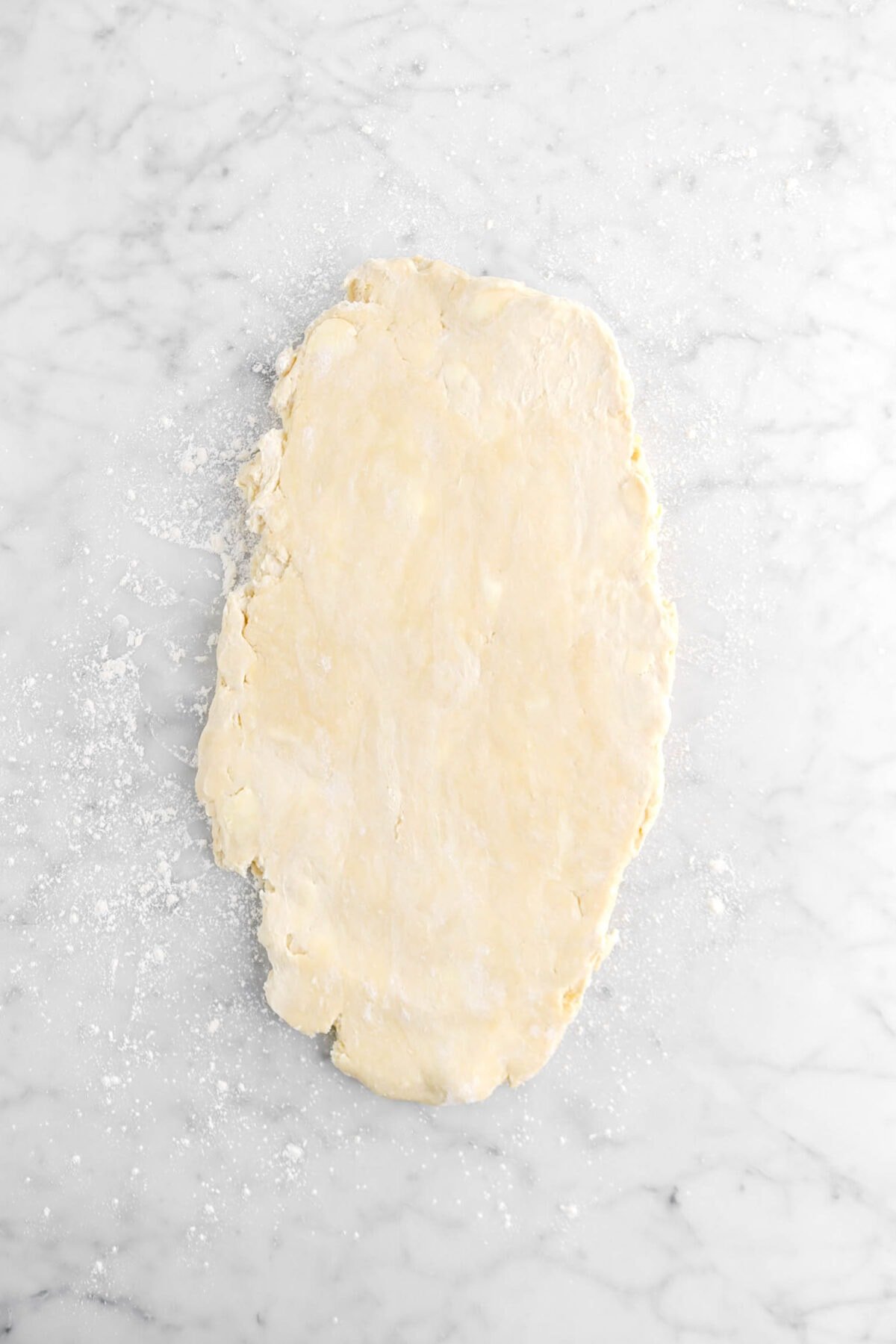 puff pastry dough rolled into an oval on marble surface