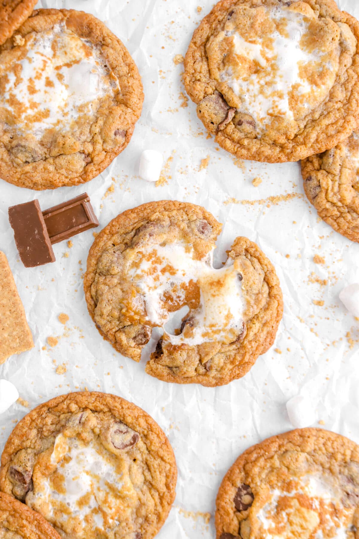 close up of s'mores cookie pulled apart on crumpled parchment paper with five more cookies around