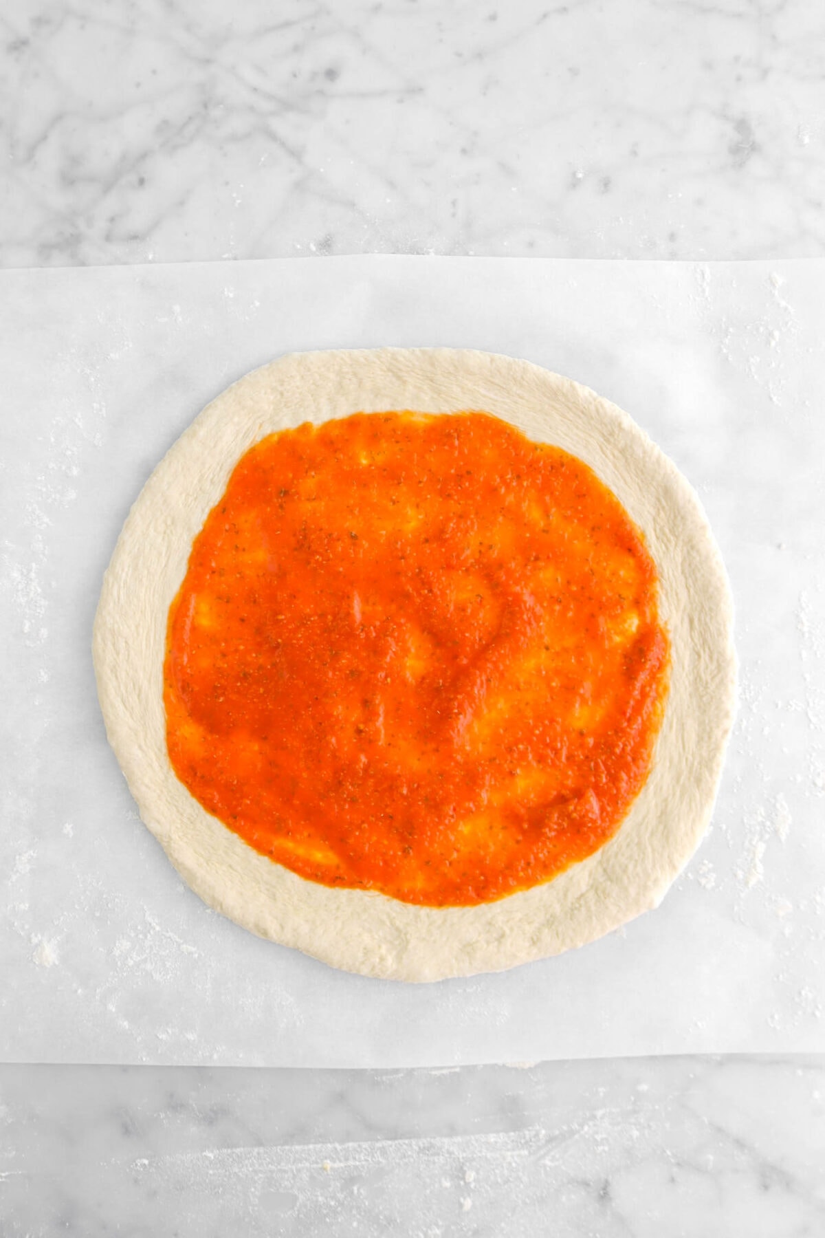 tomato sauce spread across pizza dough
