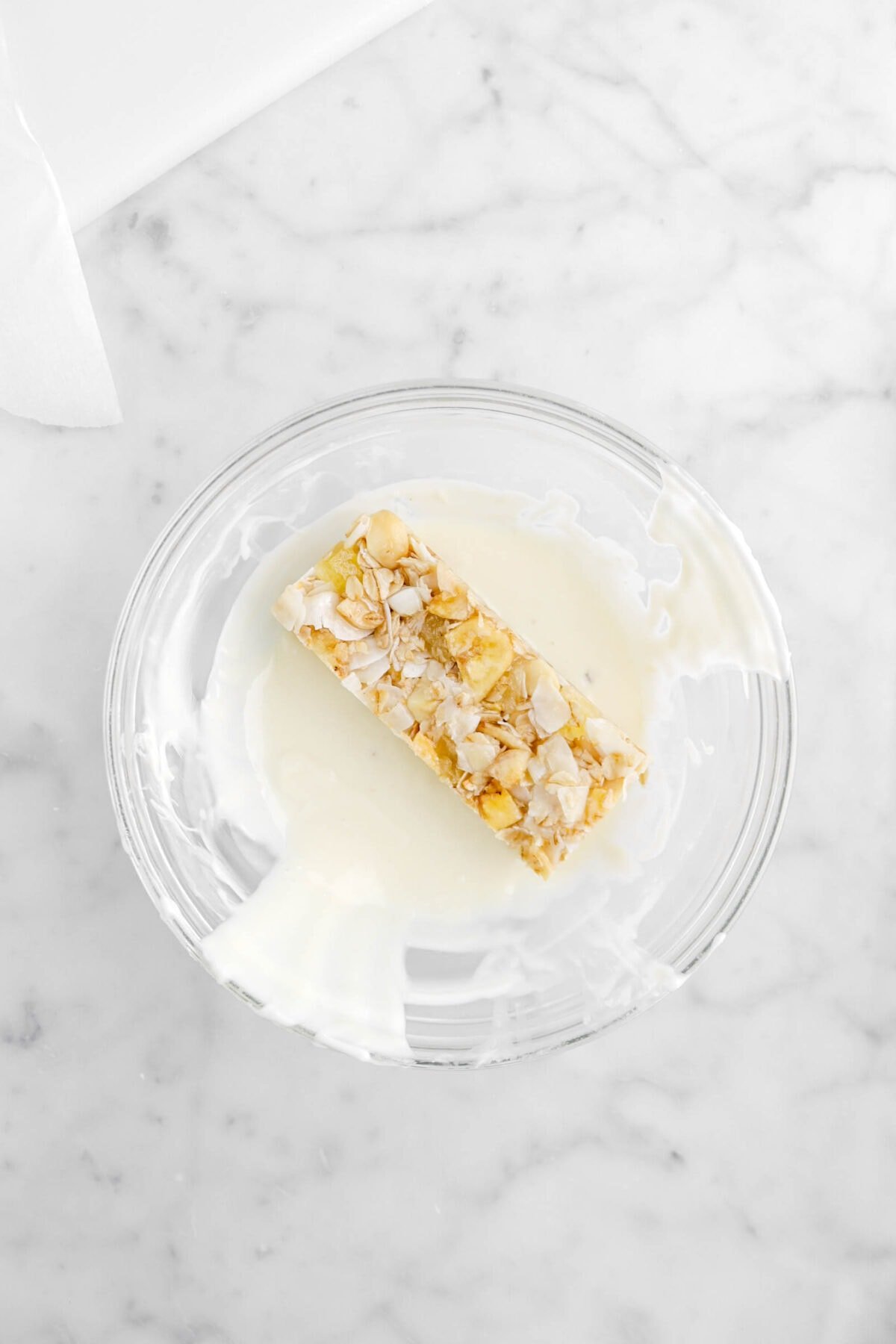 granola bar in bowl of melted white chocolate