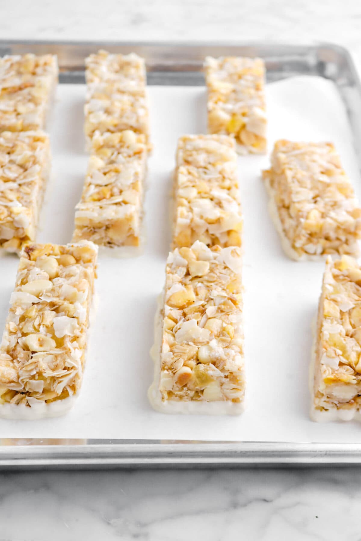 granola bars on lined sheet pan with bottoms dipped in white chocolate