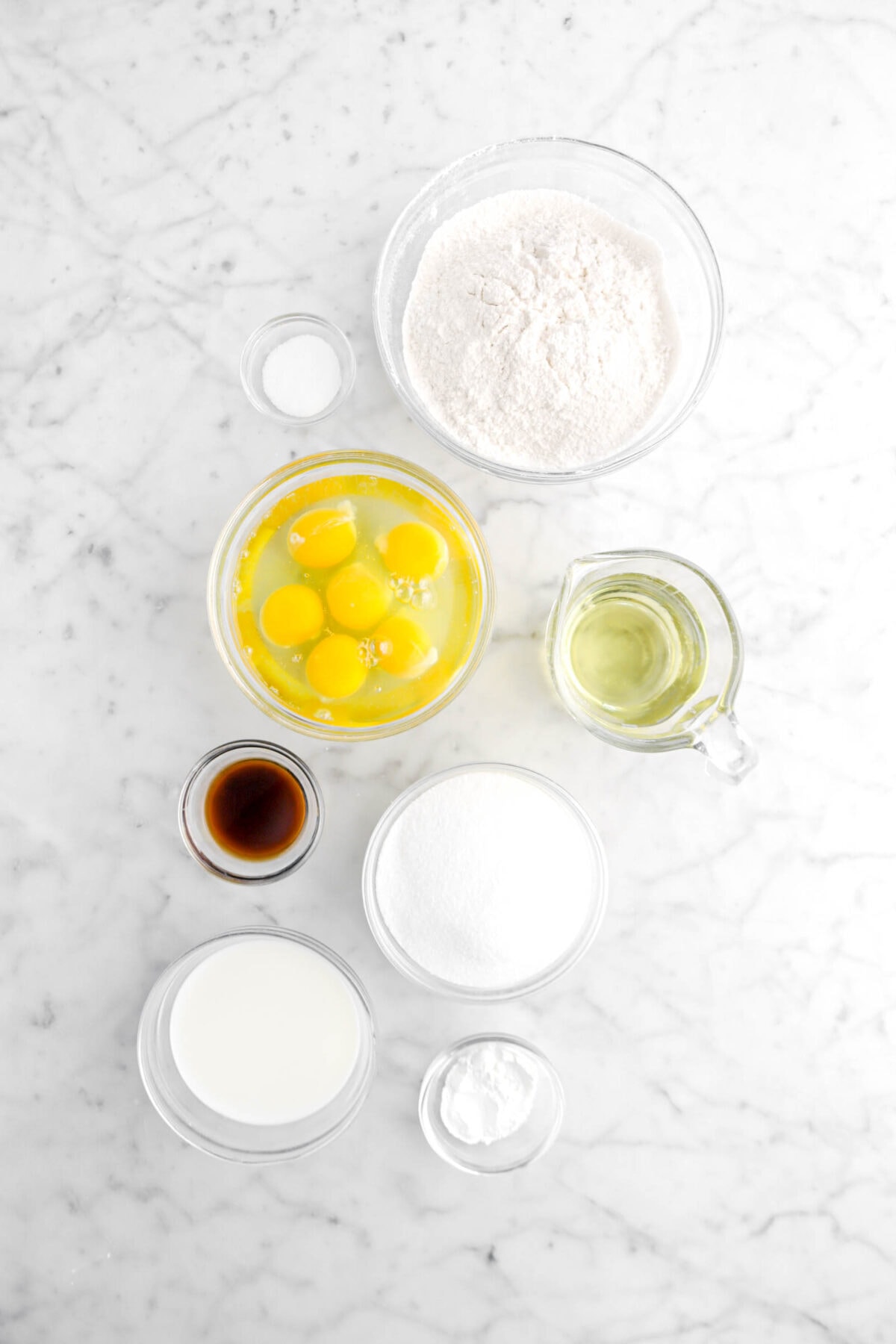 salt, flour, eggs, vegetable oil, vanilla, sugar, milk, and baking powder on marble surface