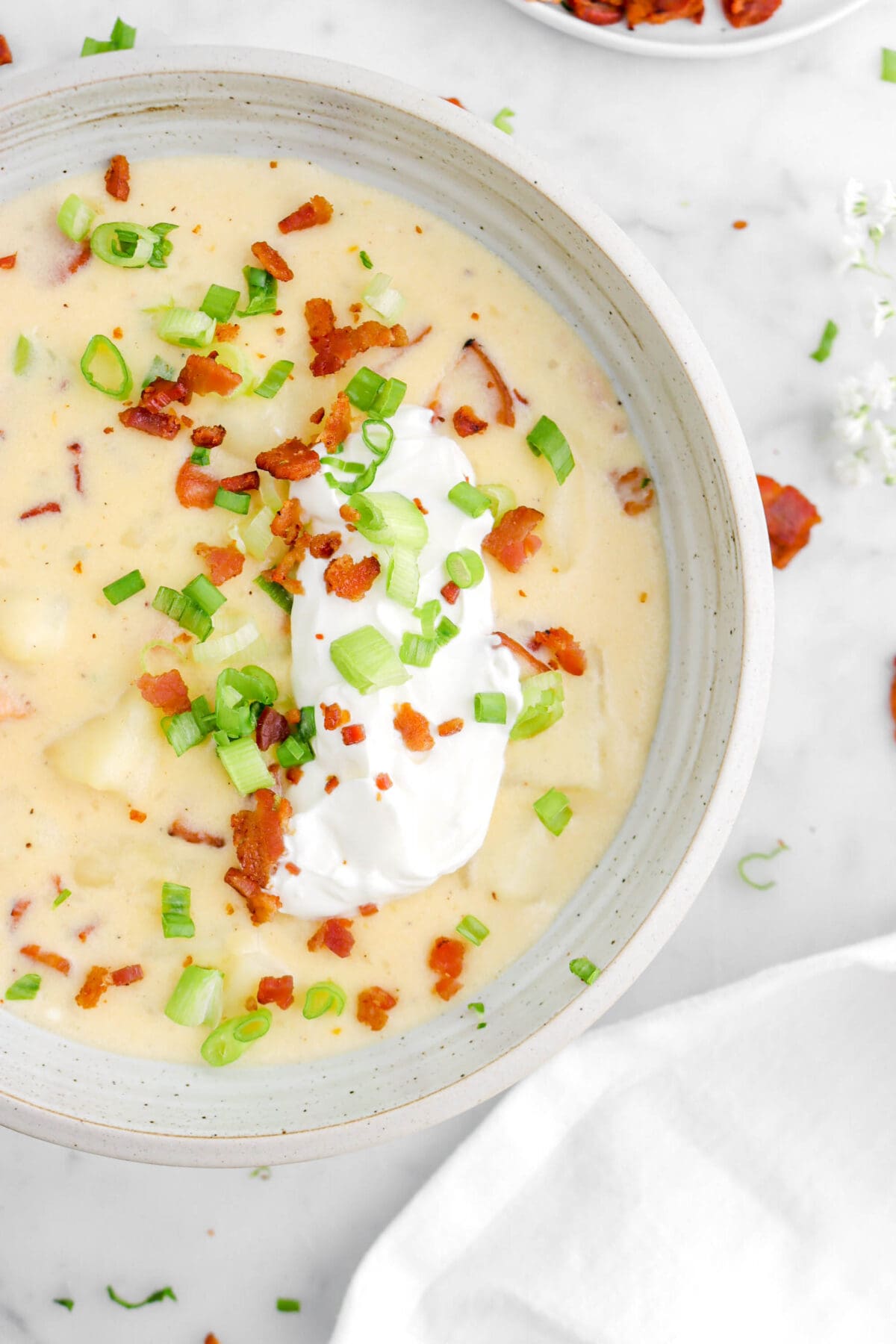 cropped close up of baked potato soup with sour cream, green onions, and bacon on top