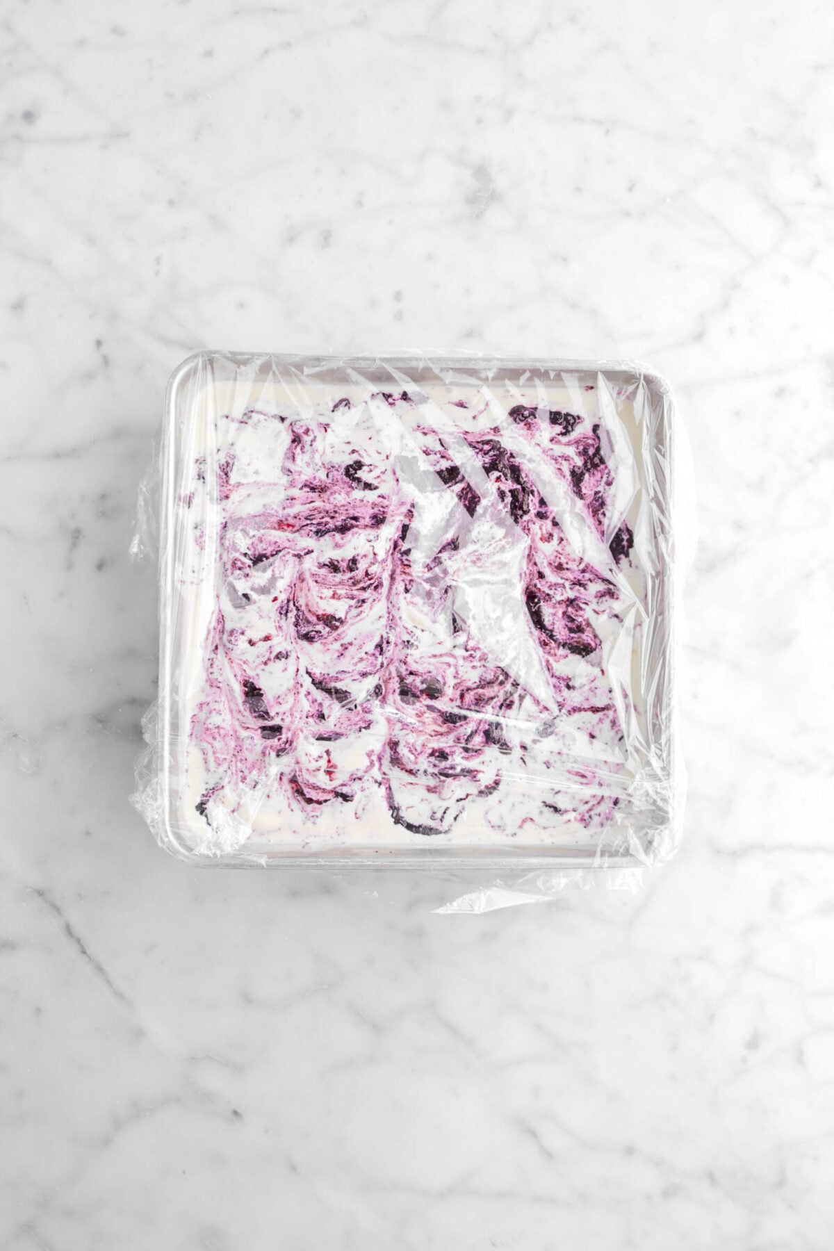 blueberry cheesecake ice cream covered with plastic wrap on marble surface