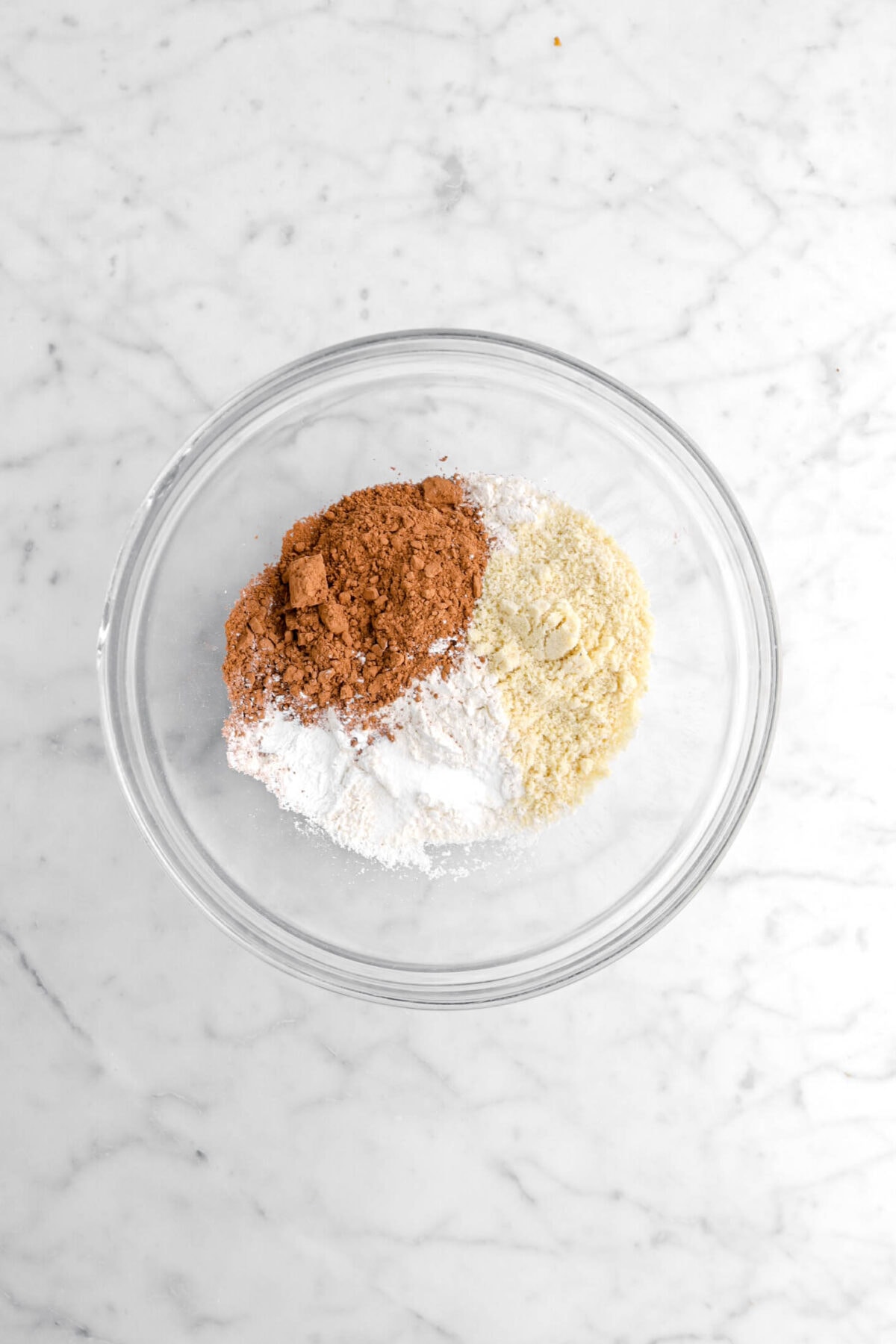 cocoa powder, almond flour, flour, baking powder, and salt on marble surface