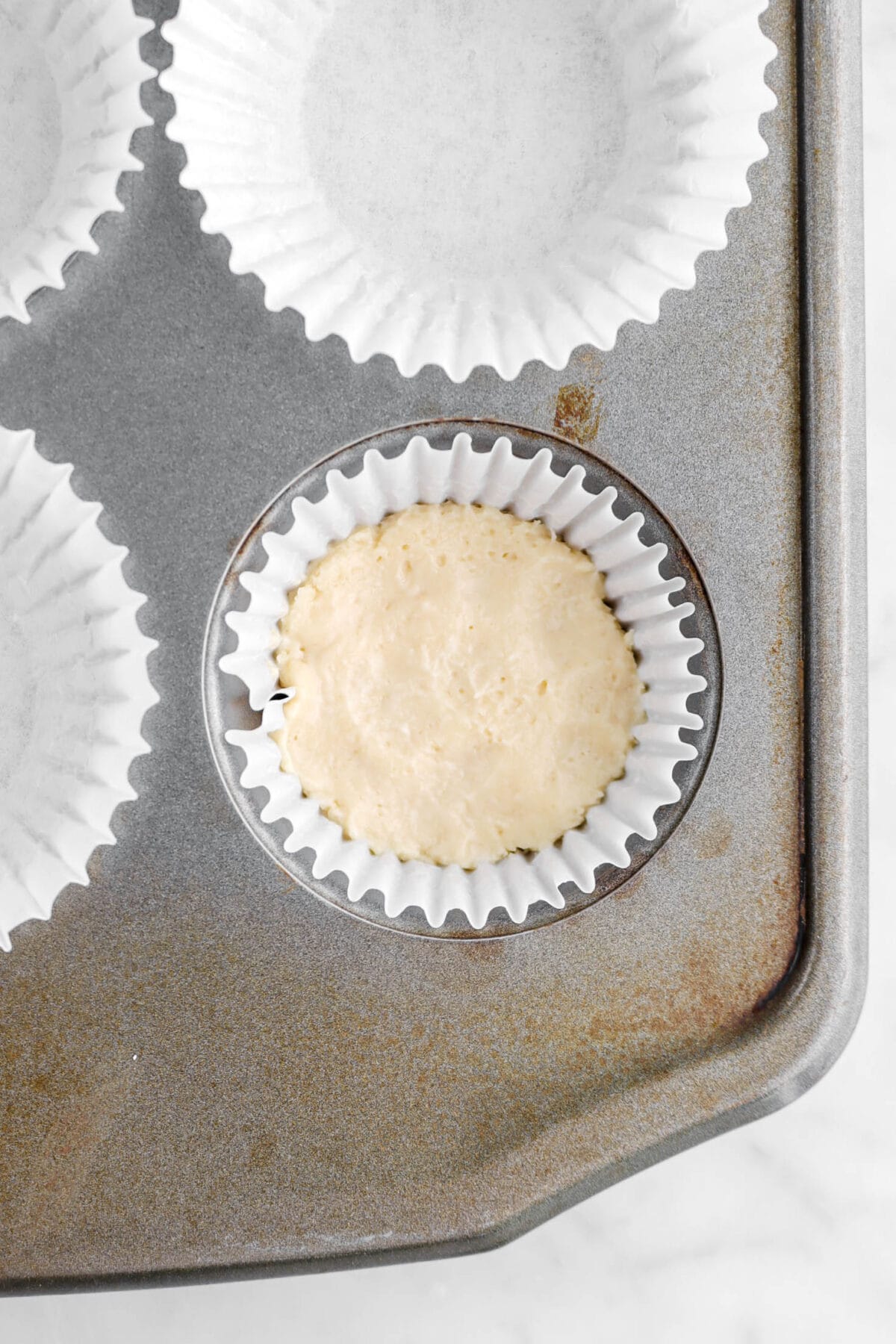cake batter in cupcake paper in muffin pan
