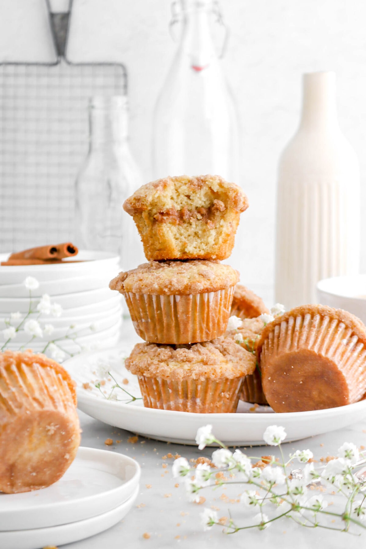 three stacked muffins with bite missing from top muffin on white plate