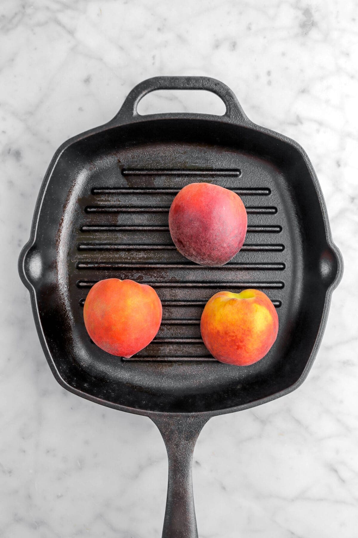 three peaches face down on grill pan
