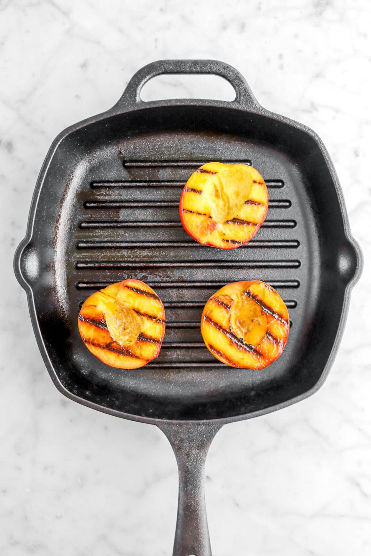 three grilled peaches on grill pan