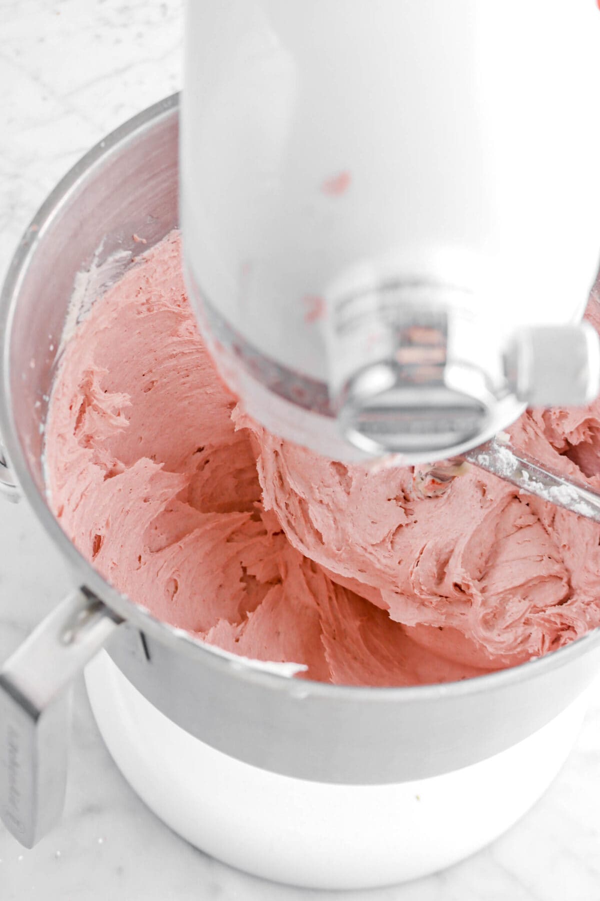 milk stirred into strawberry buttercream in stand mixer
