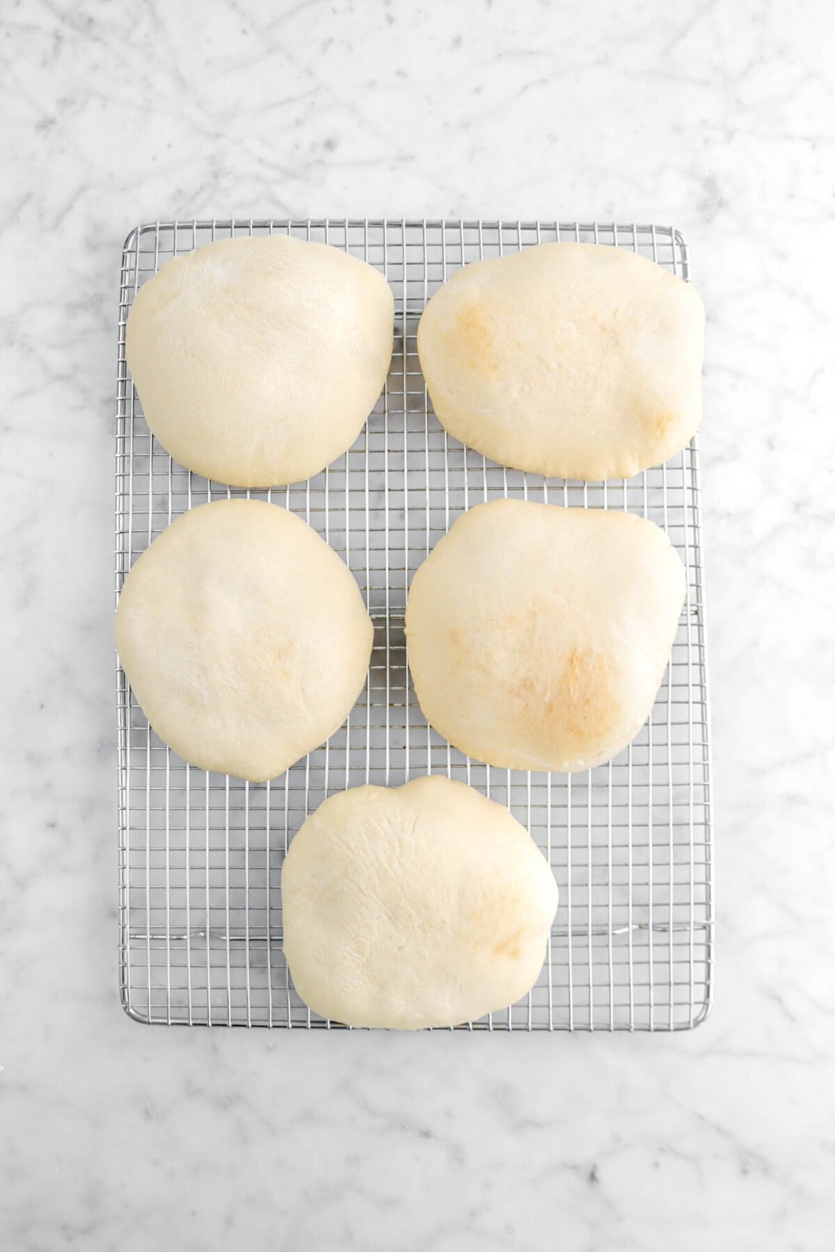 five baked pitas on wire cooling rack