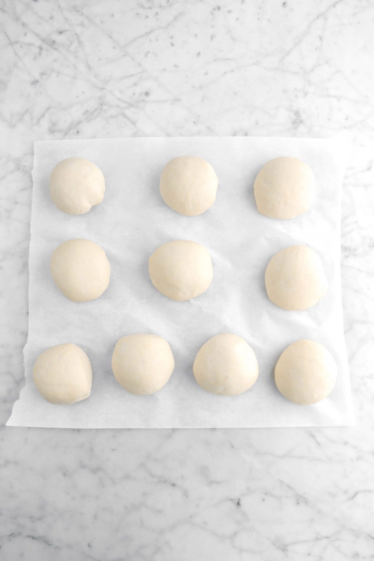 ten proofed dough balls on parchment paper
