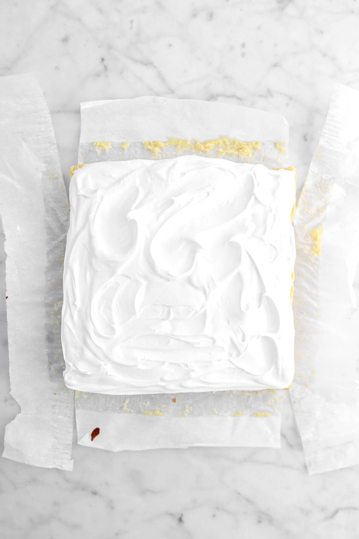 meringue spread across key lime pie on parchment paper