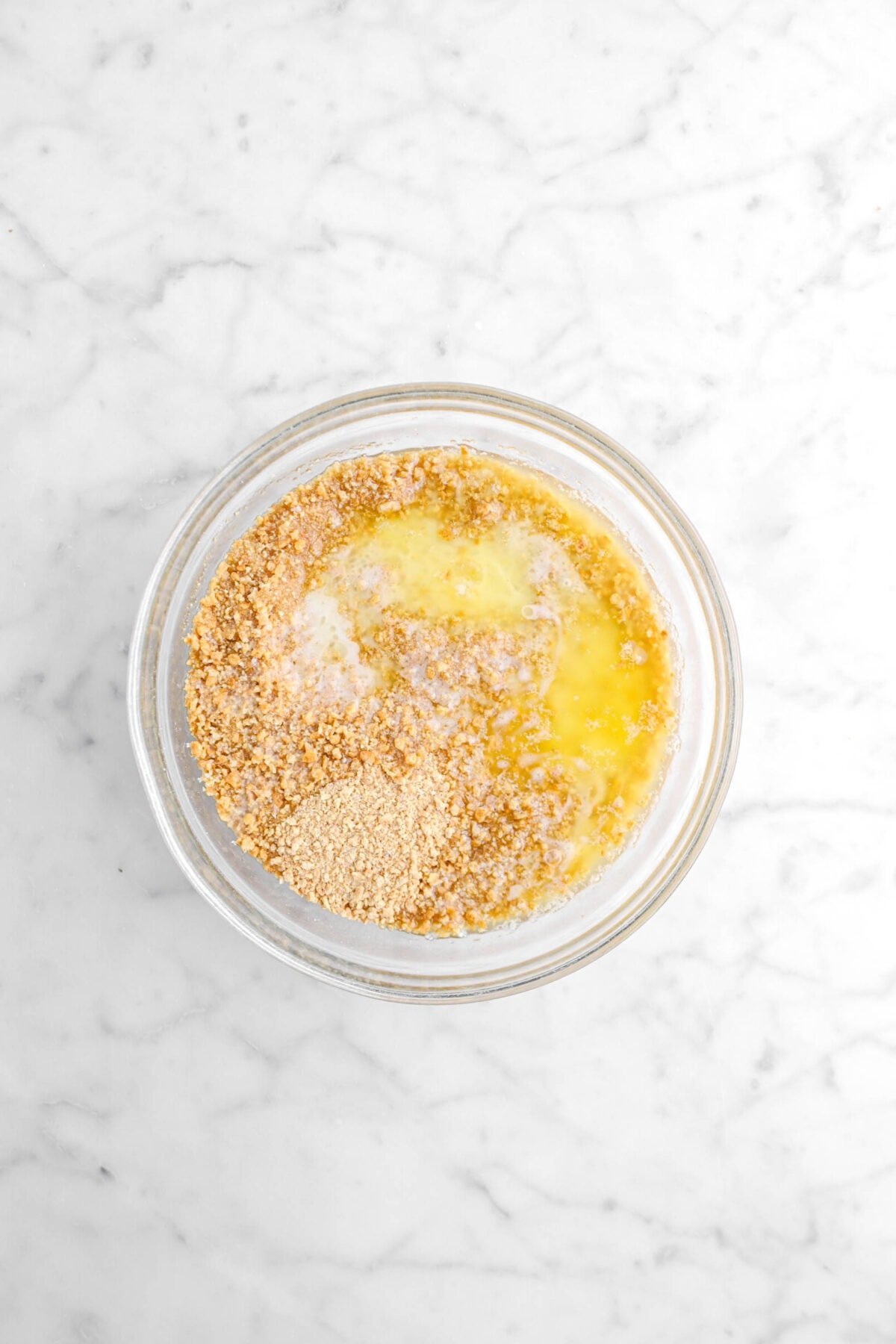 melted butter and graham cracker crumbs in glass bowl