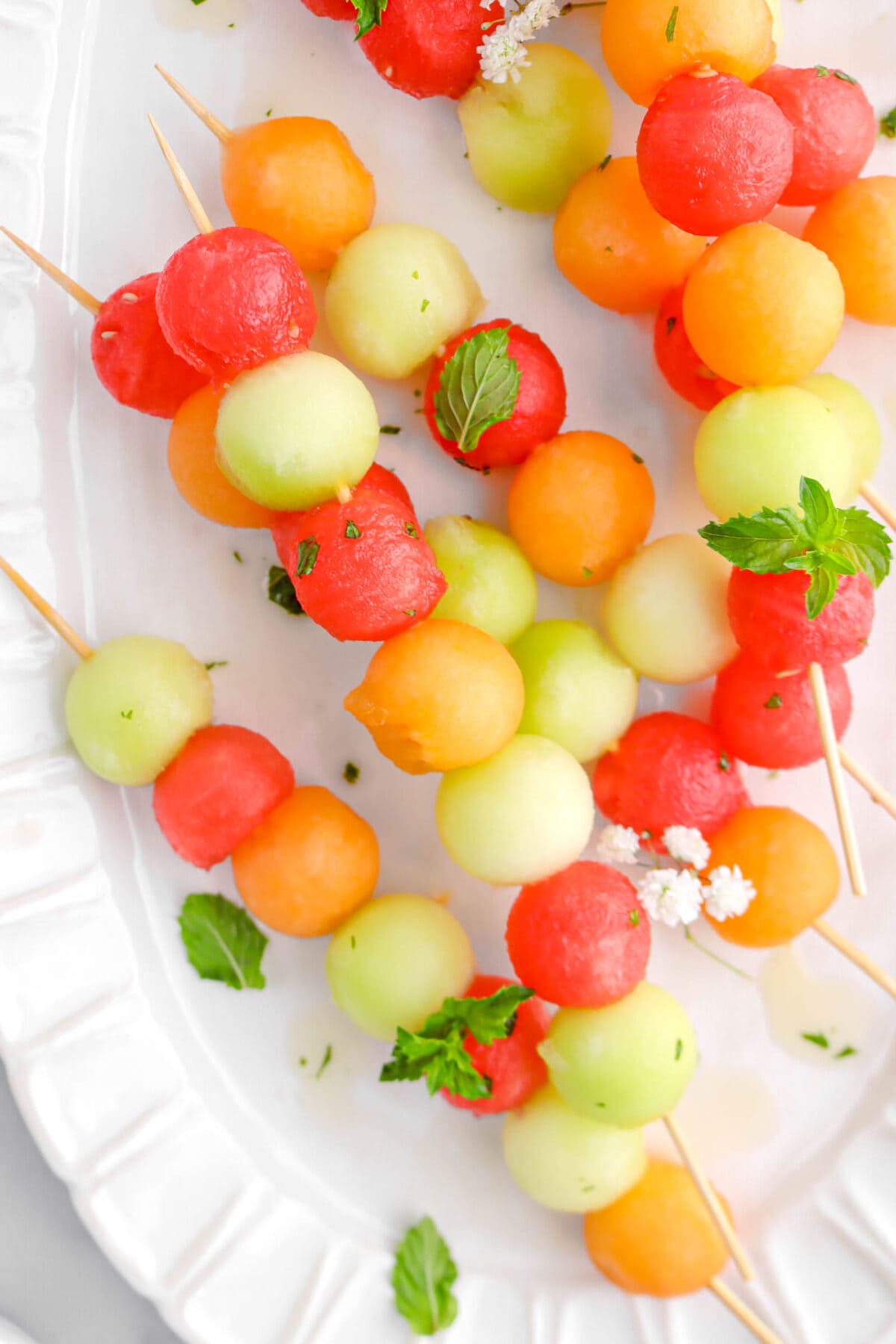 close up of melon skewers on white plate