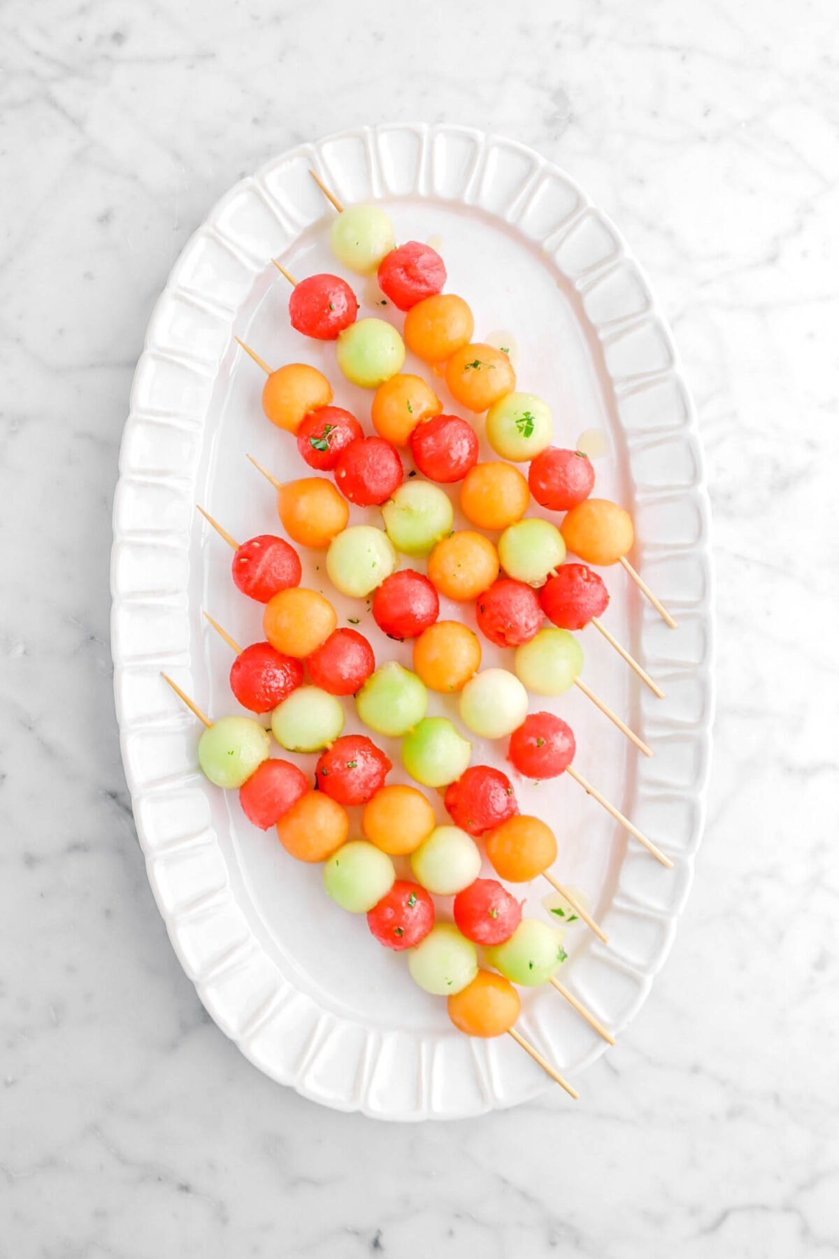 melon skewers with honey drizzle on oval white platter