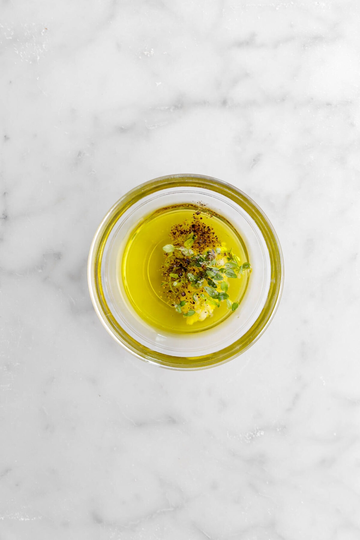 olive oil, garlic, thyme, and pepper in glass bowl