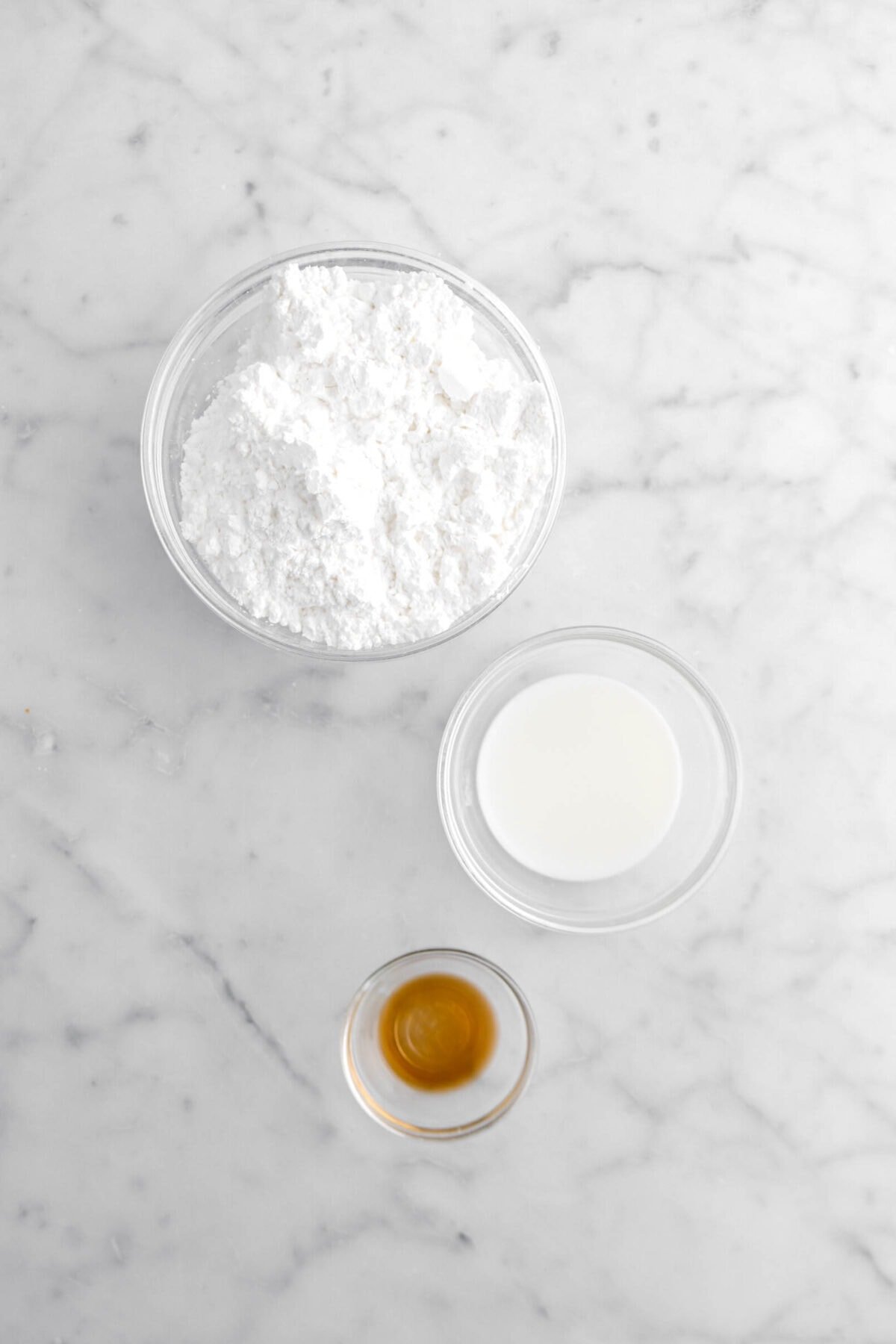 Powdered sugar, milk, and vanilla on marble surface