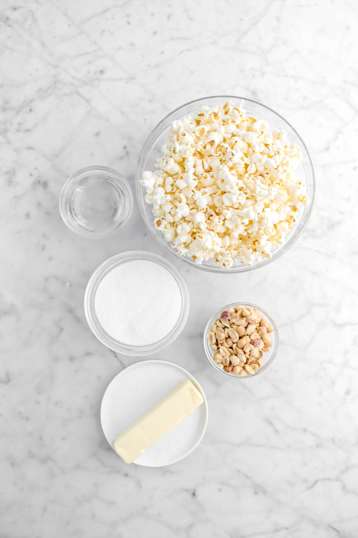 water, popcorn, sugar, peanuts, and butter on marble surface