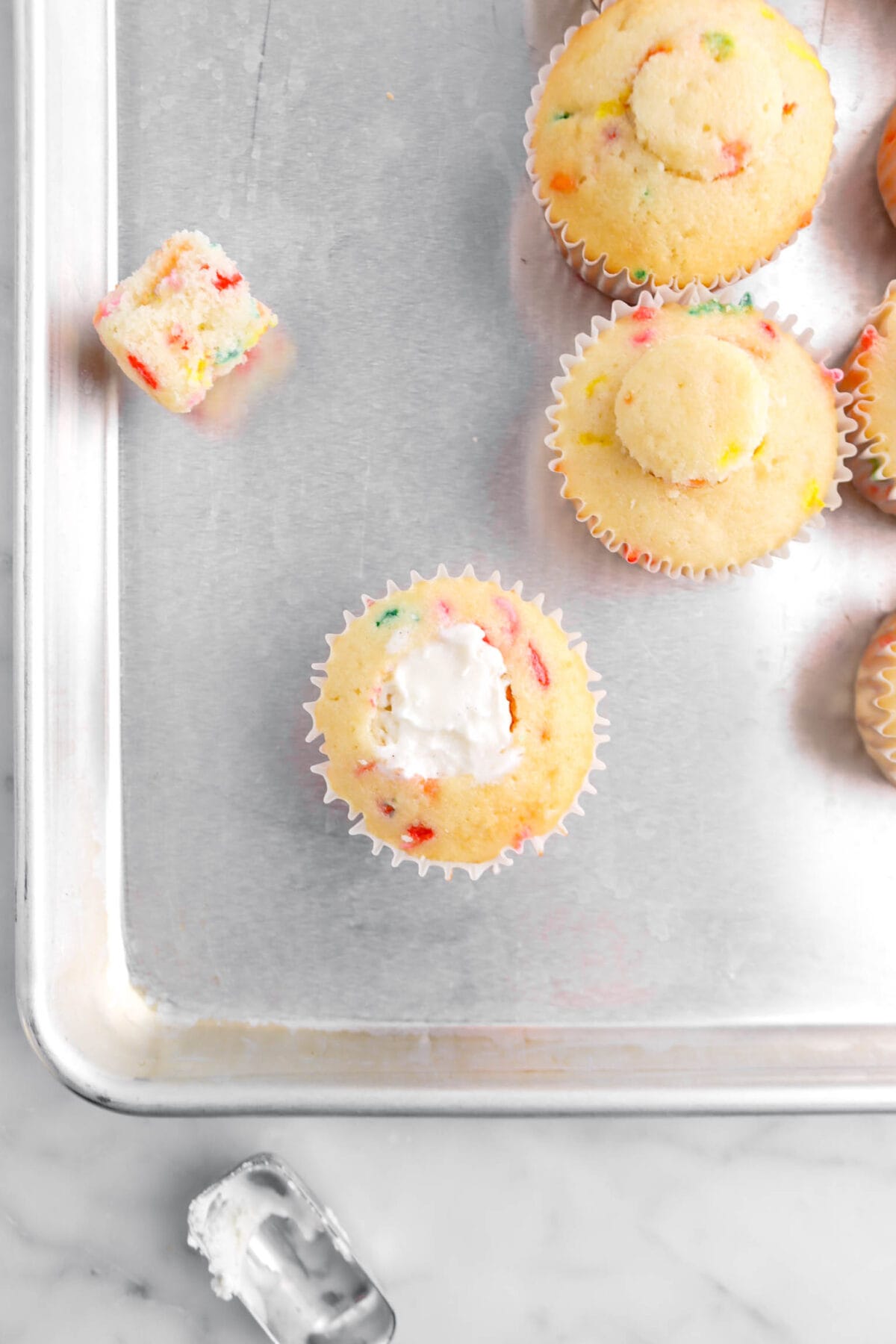 funfetti cupcake filled with vanilla ice cream on sheet pan with more cupcakes beside