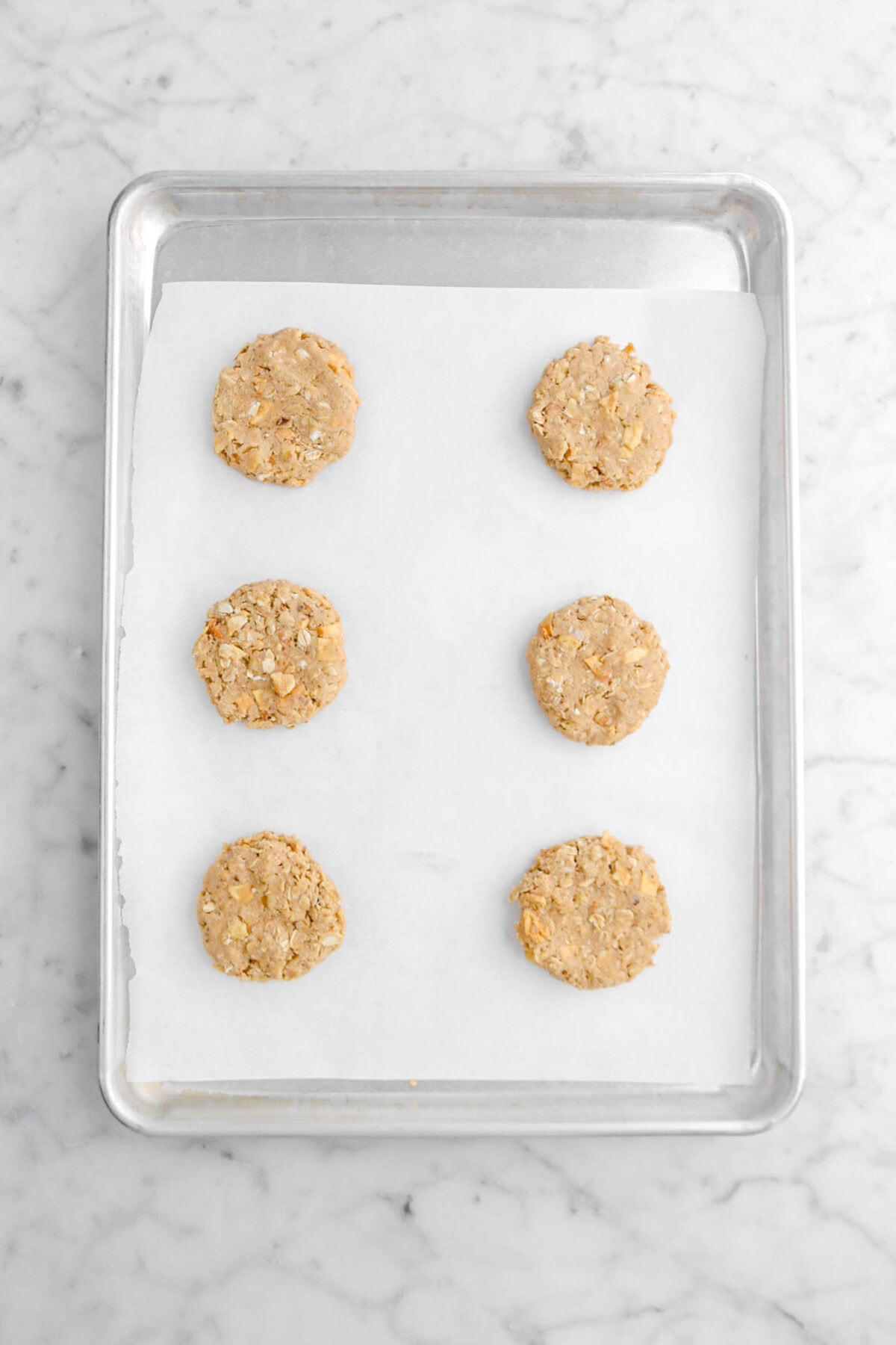 six unbaked cookies on lined sheet pan.
