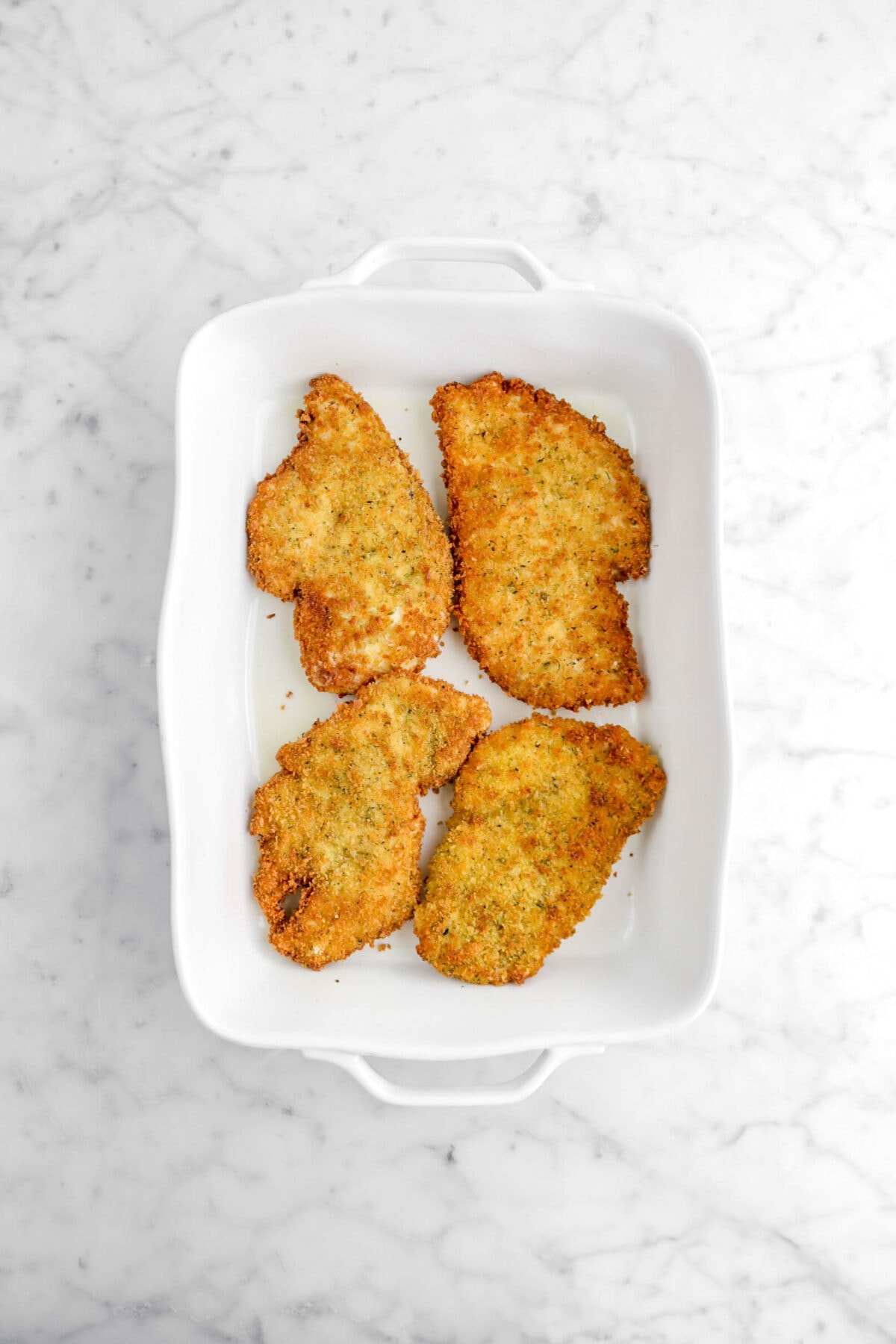 four fried chicken breasts in large white casserole