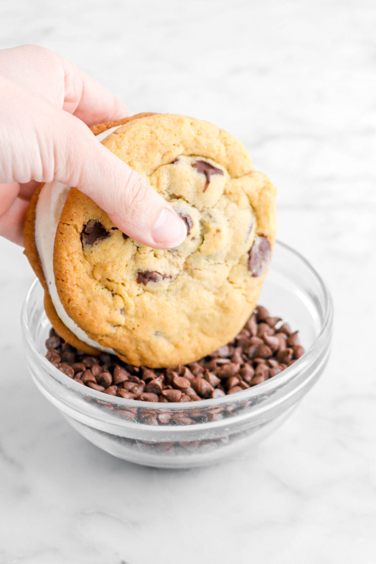 cookie being dipped in bowl of chocolate chips