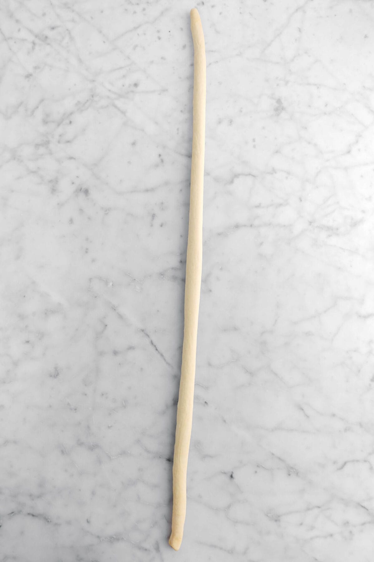 long rope of dough on marble surface.