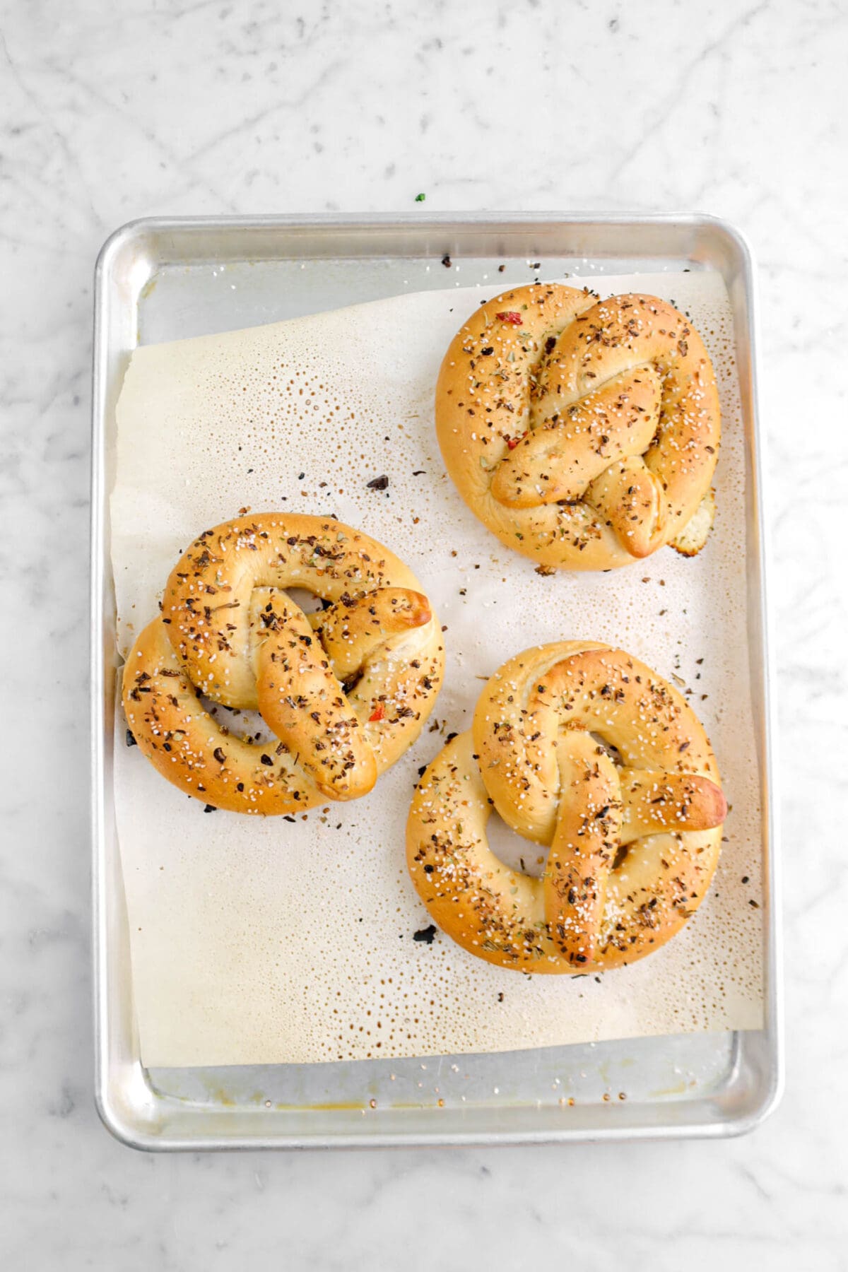 three baked pretzels on lined sheet pan.