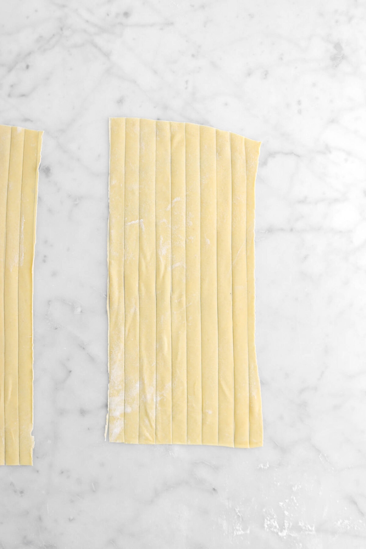 pasta cut into strips on marble surface.