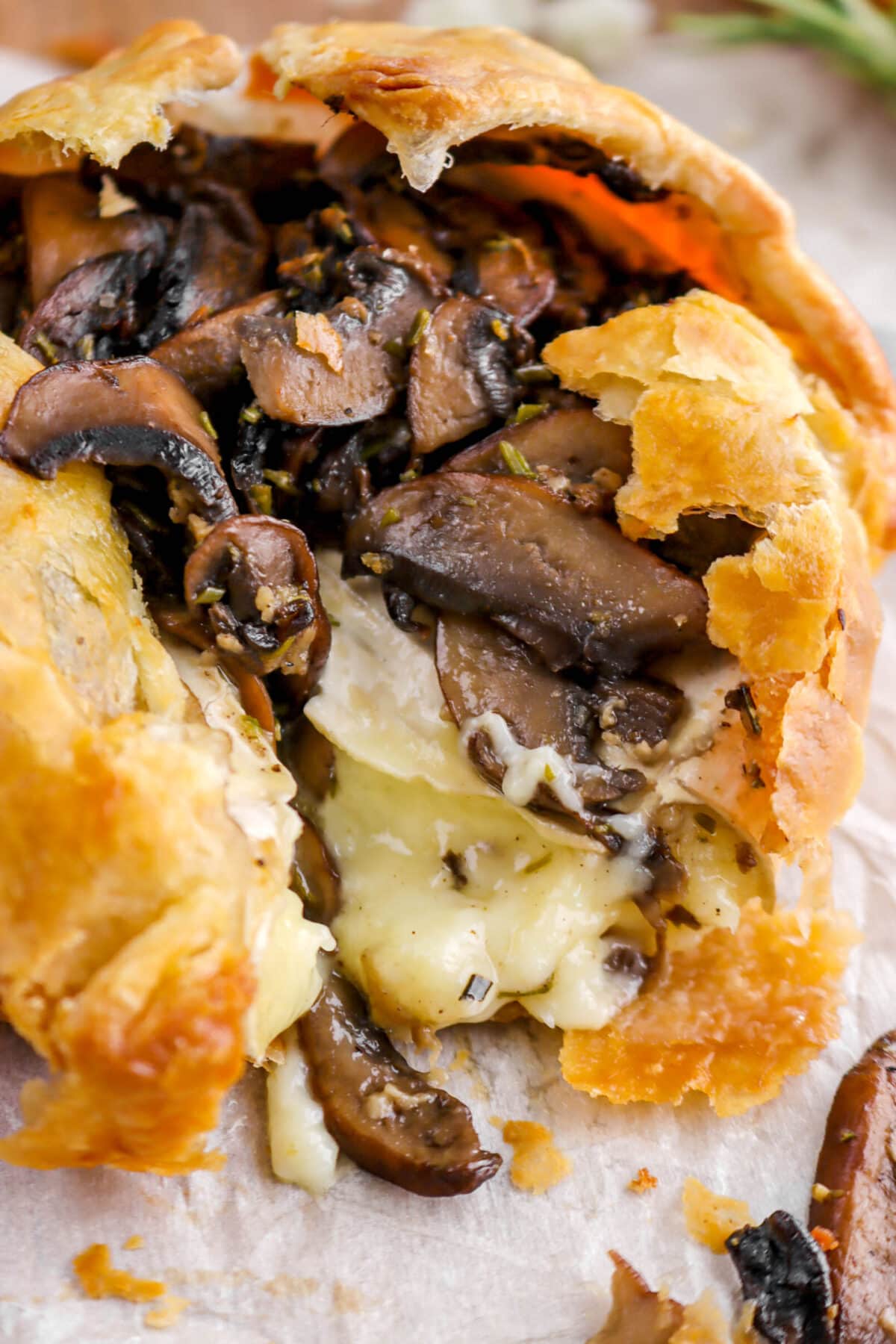 close up of baked brie with mushrooms on top and puff pastry.