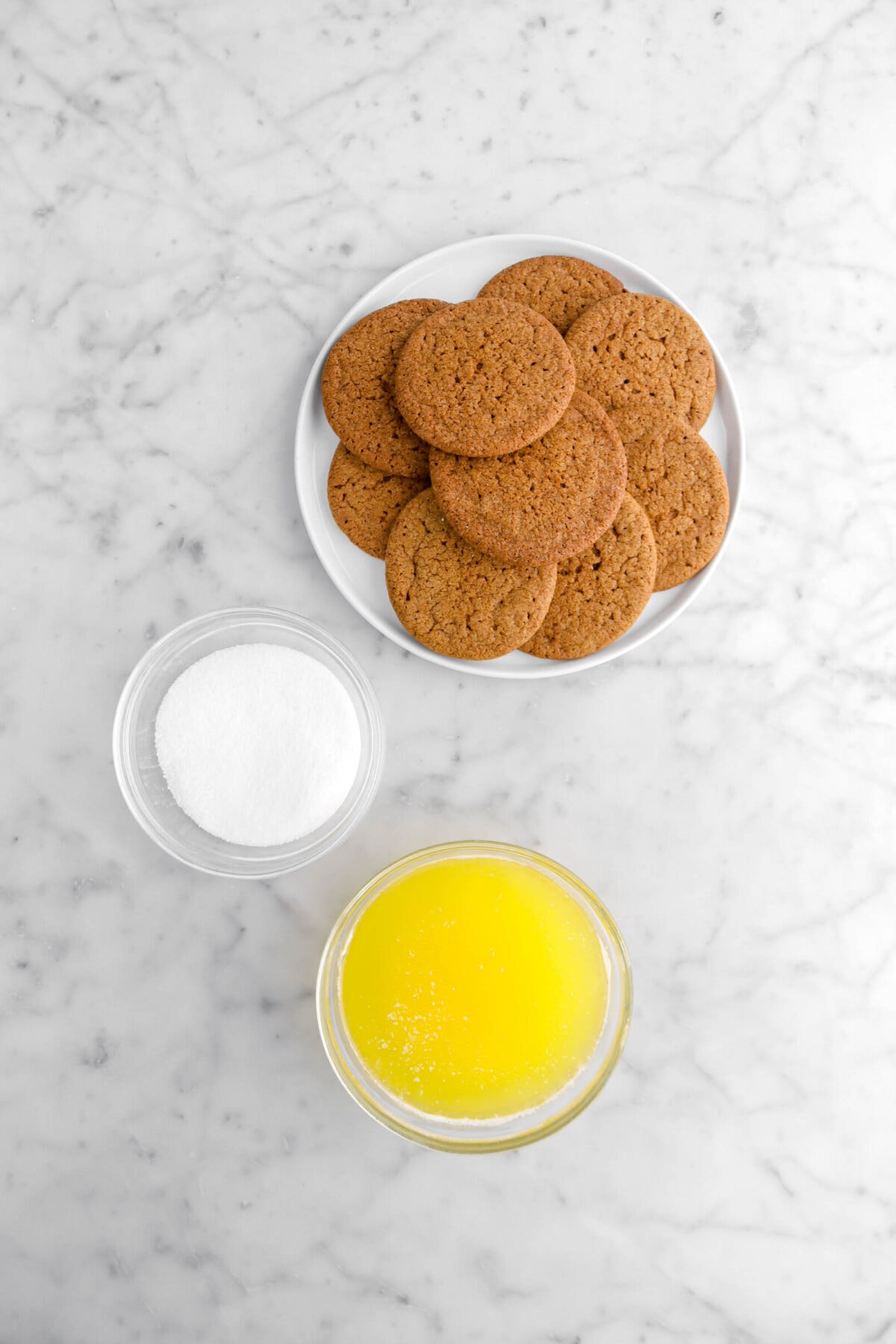 gingersnap cookies, sugar, and melted butter on marble surface.