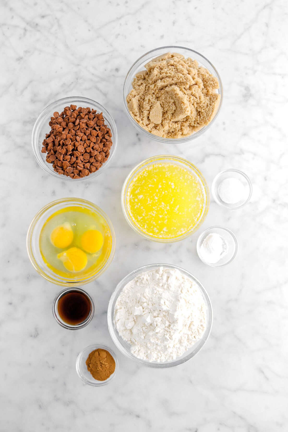 brown sugar, cinnamon chips, melted butter, eggs, salt, baking powder, flour, pumpkin pie spice, and vanilla on marble surface.