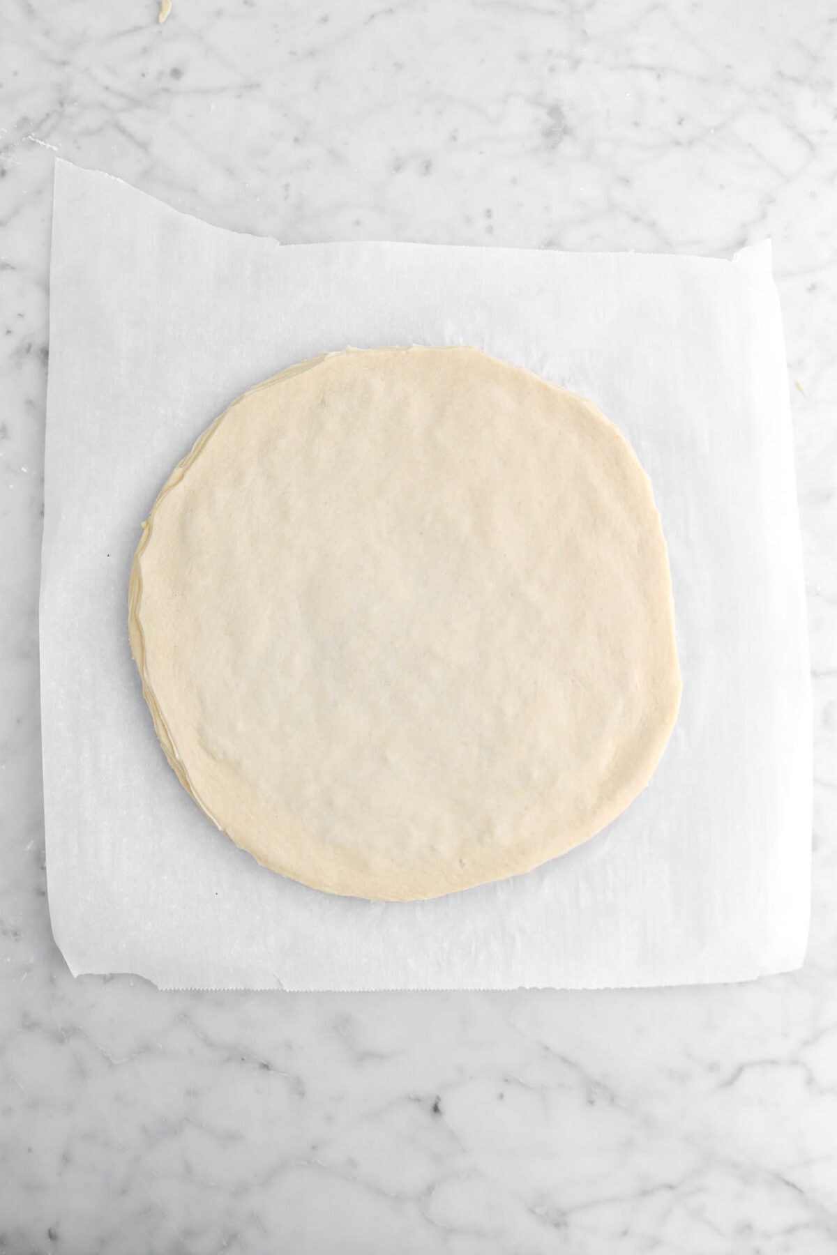 round circle of dough laid over pesto layer.