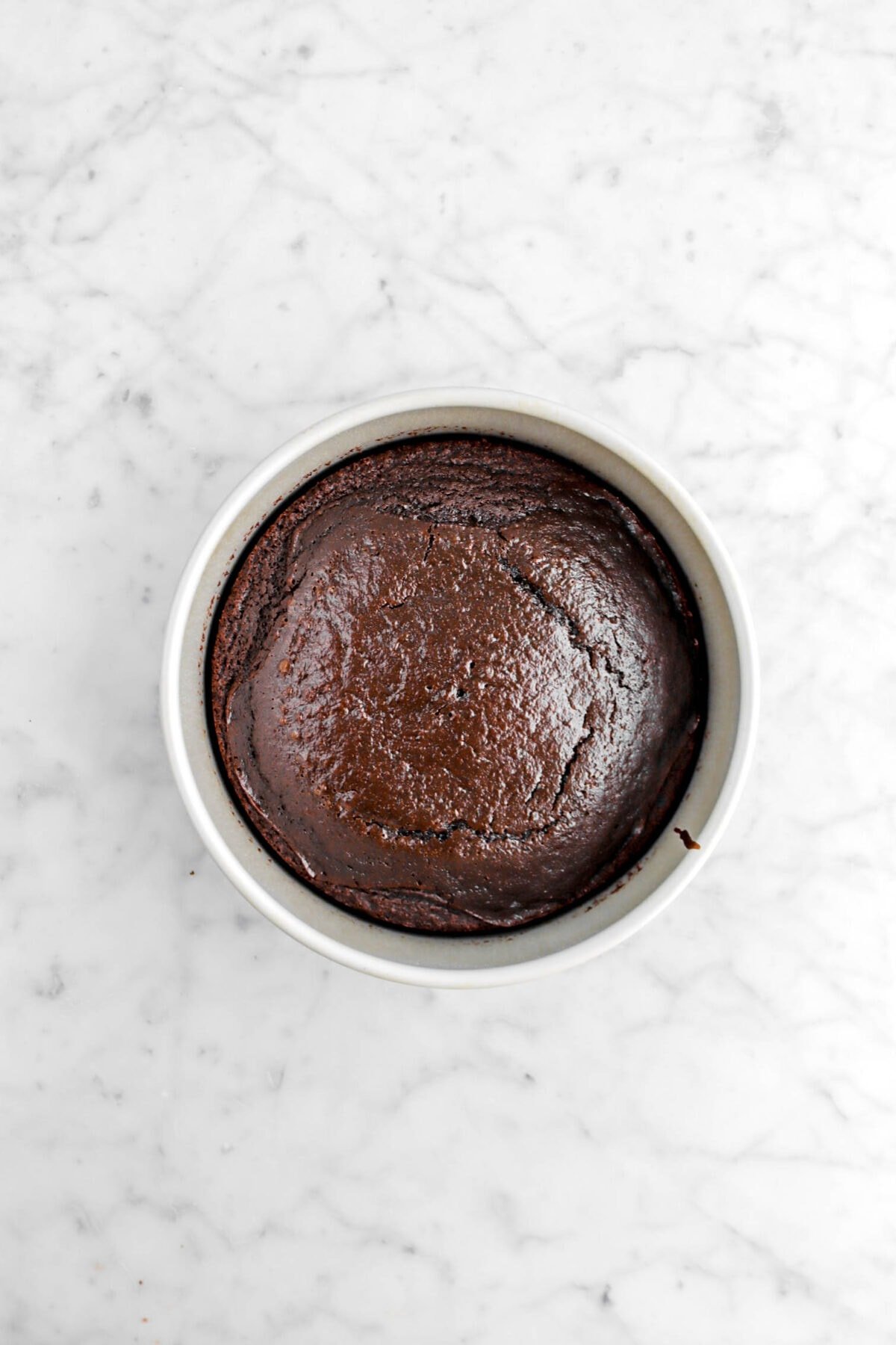 baked chocolate cake in cake pan on marble surface.