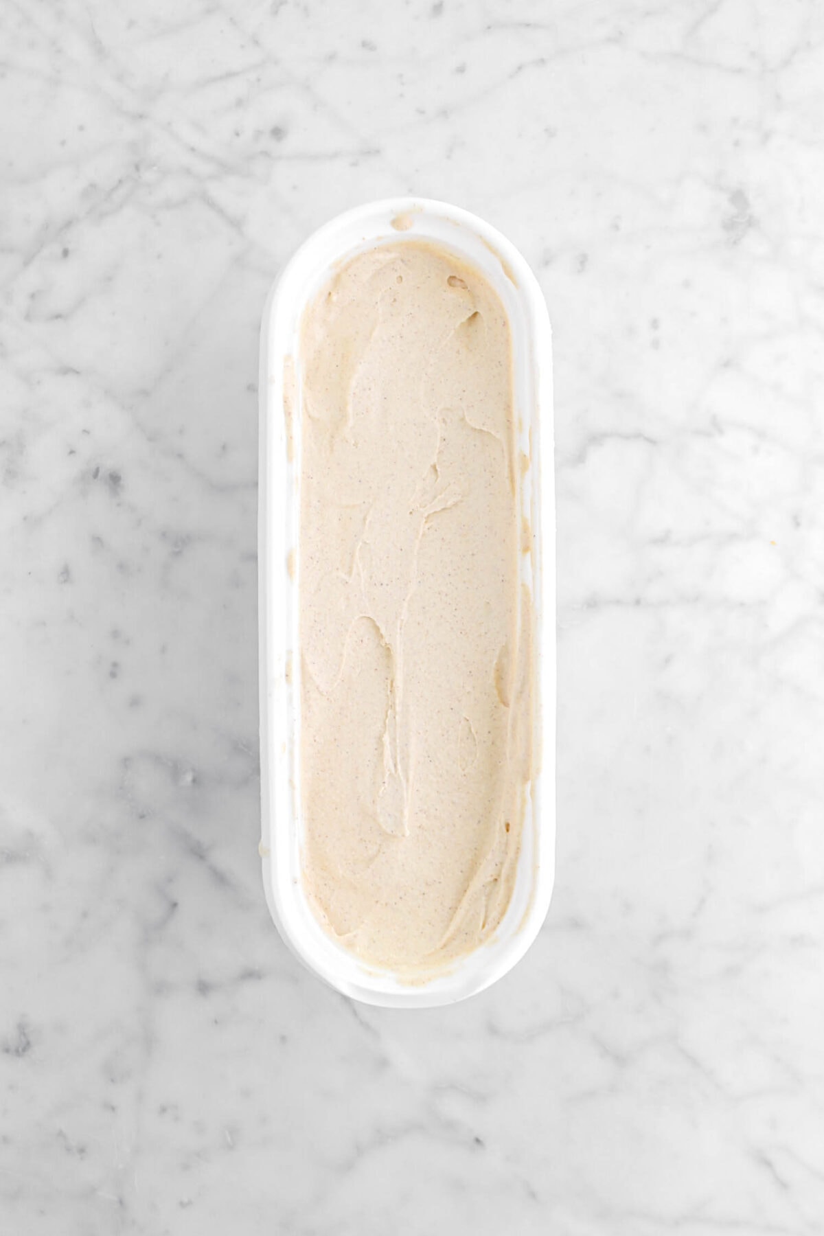 cinnamon ice cream in ice cream container on marble counter.